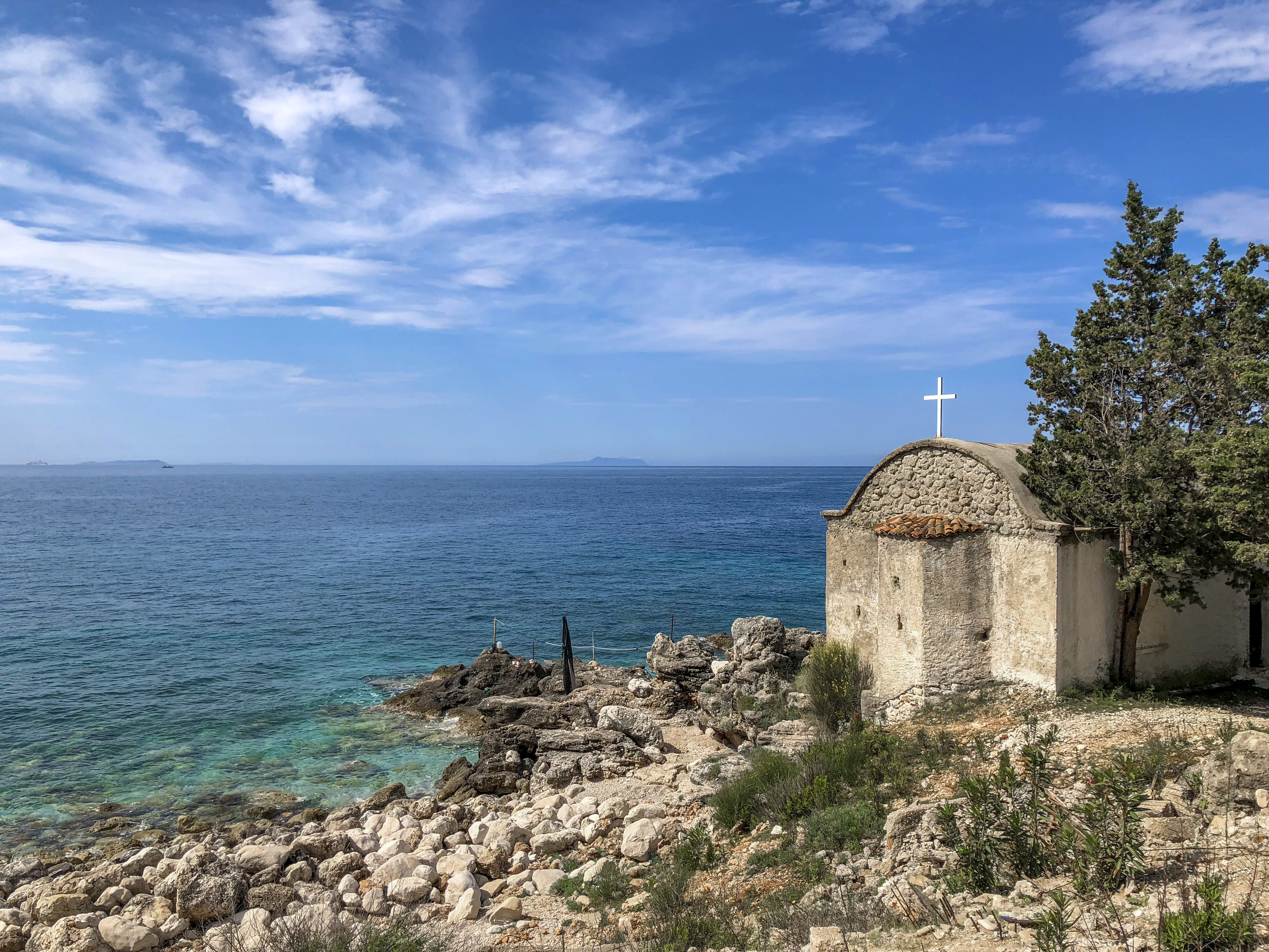 a stone building with a cross on top of it by the water