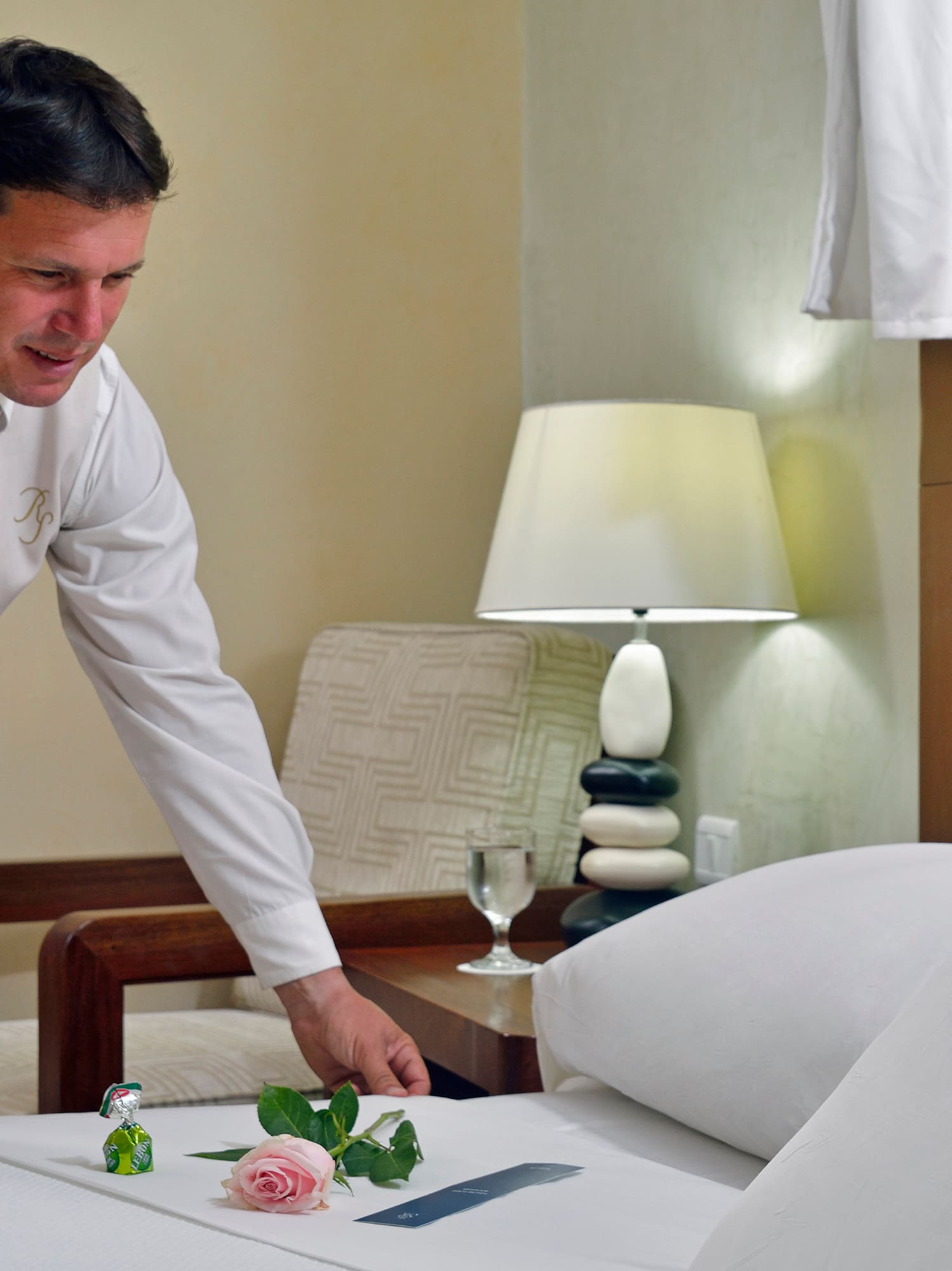 a man in a suit and tie arranging a bed