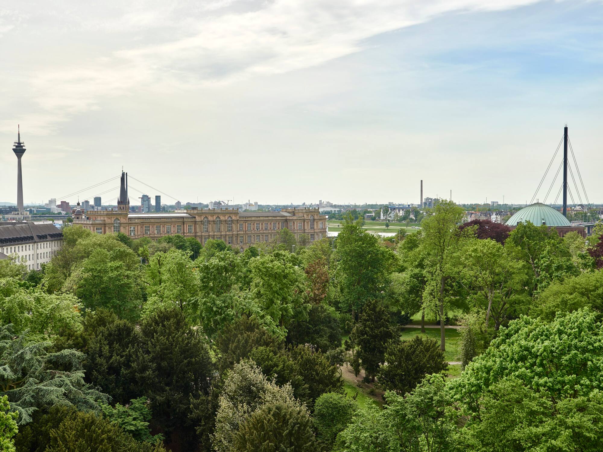 Düsseldorf city skyline over green park, featuring Rheinturm and historic building.