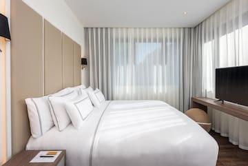 a bed with white sheets and a desk in a room with curtains