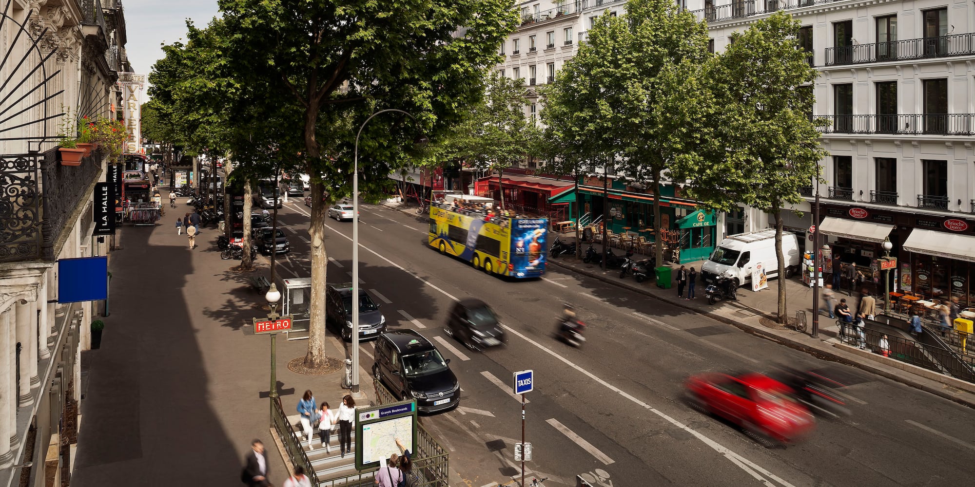 a city street with cars and people walking on the sidewalk