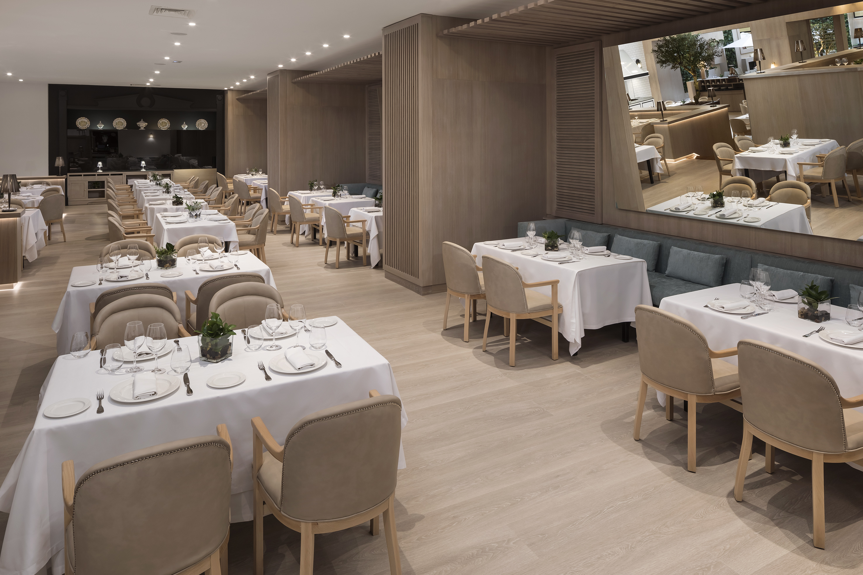Spacious, modern restaurant dining area with set tables, wood accents, and mirror.
