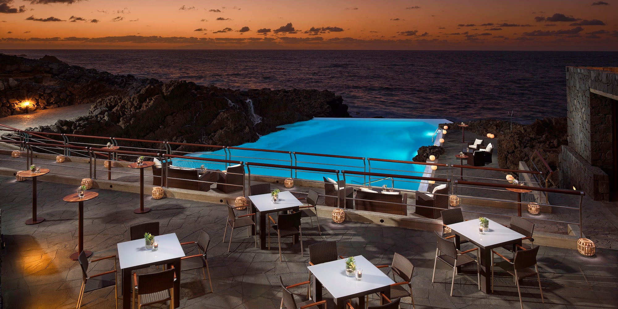 a pool with tables and chairs on a patio