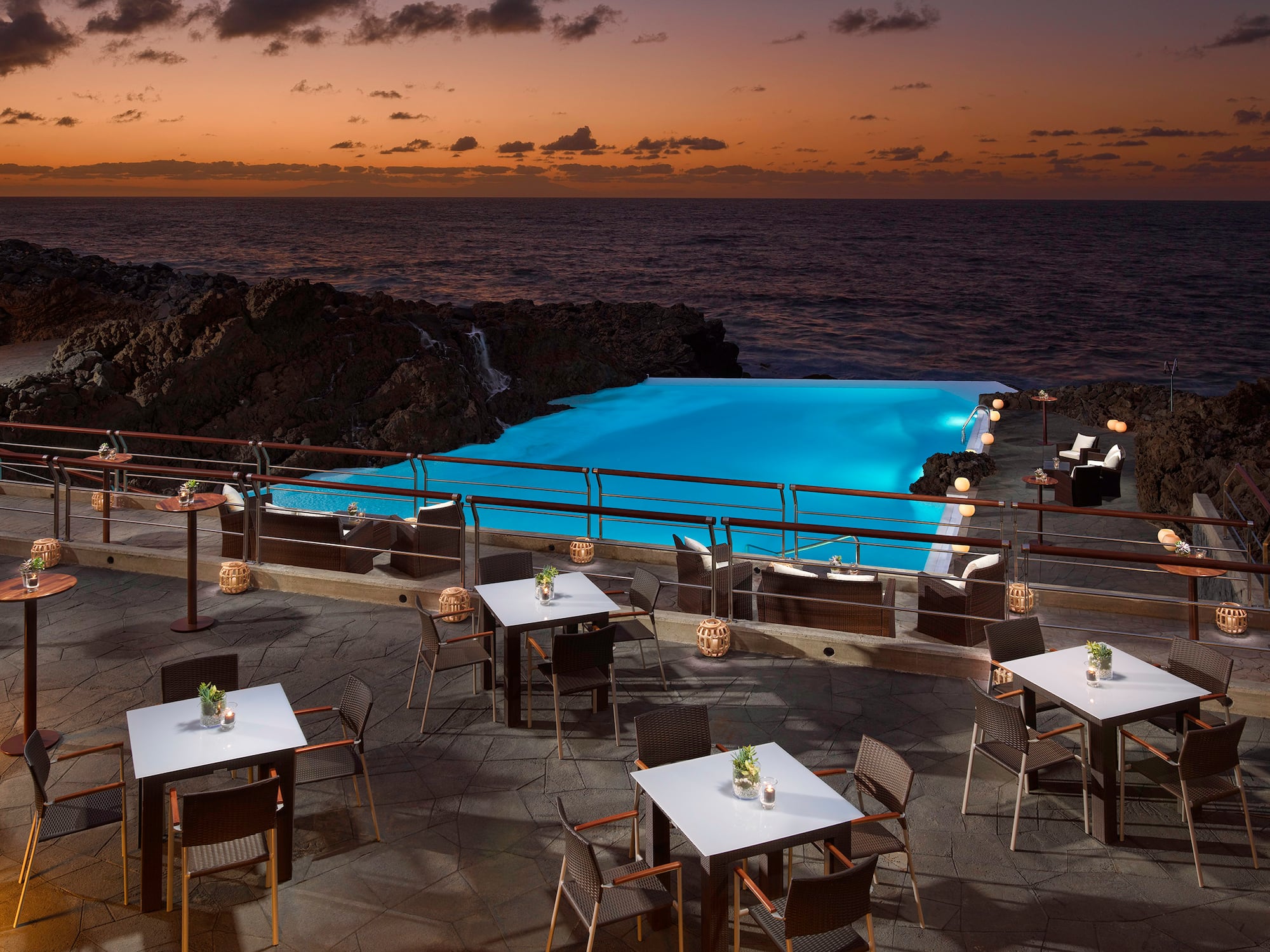 a pool with tables and chairs on a patio