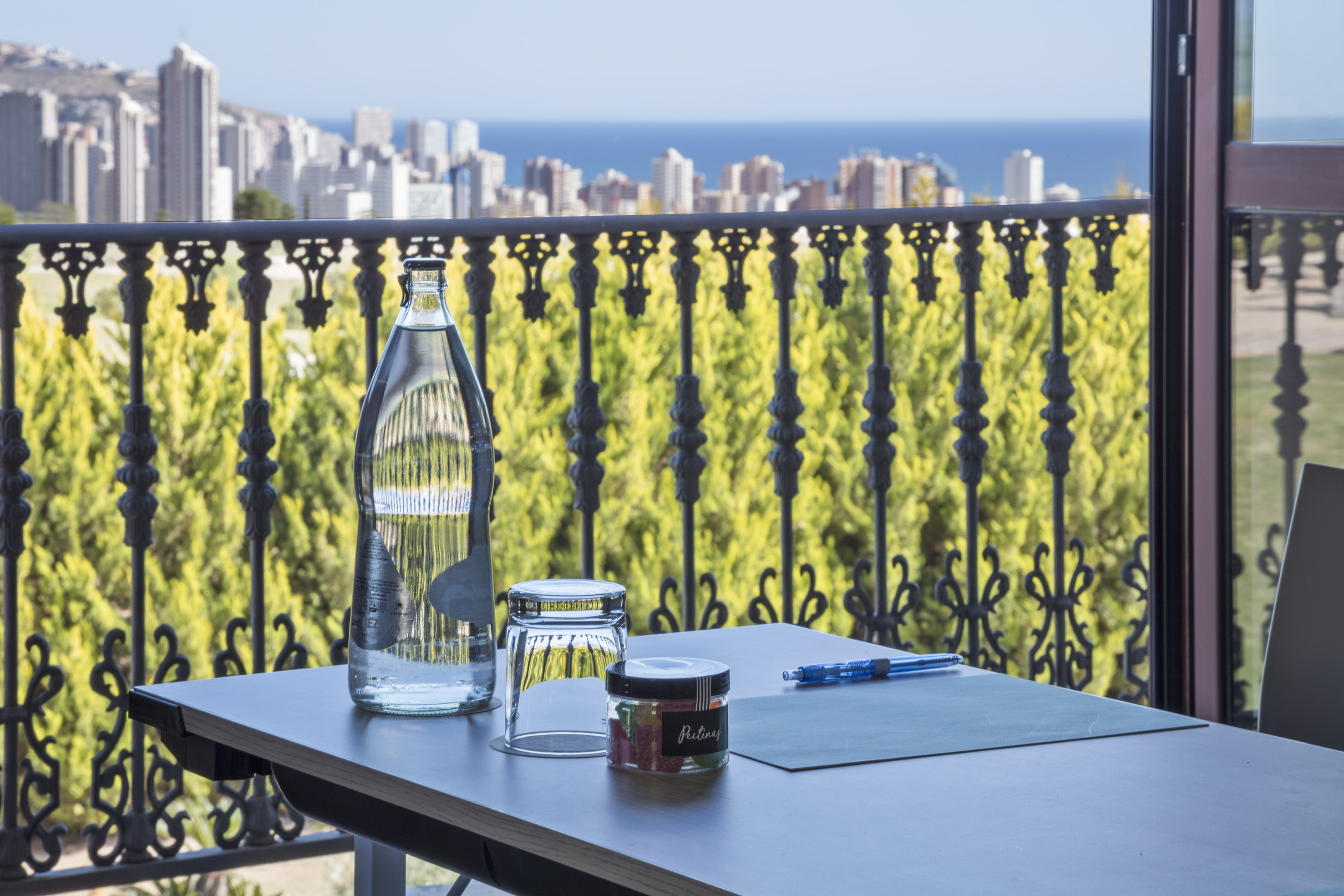 Coastal balcony view with water, candies, pen, city skyline, and sea.