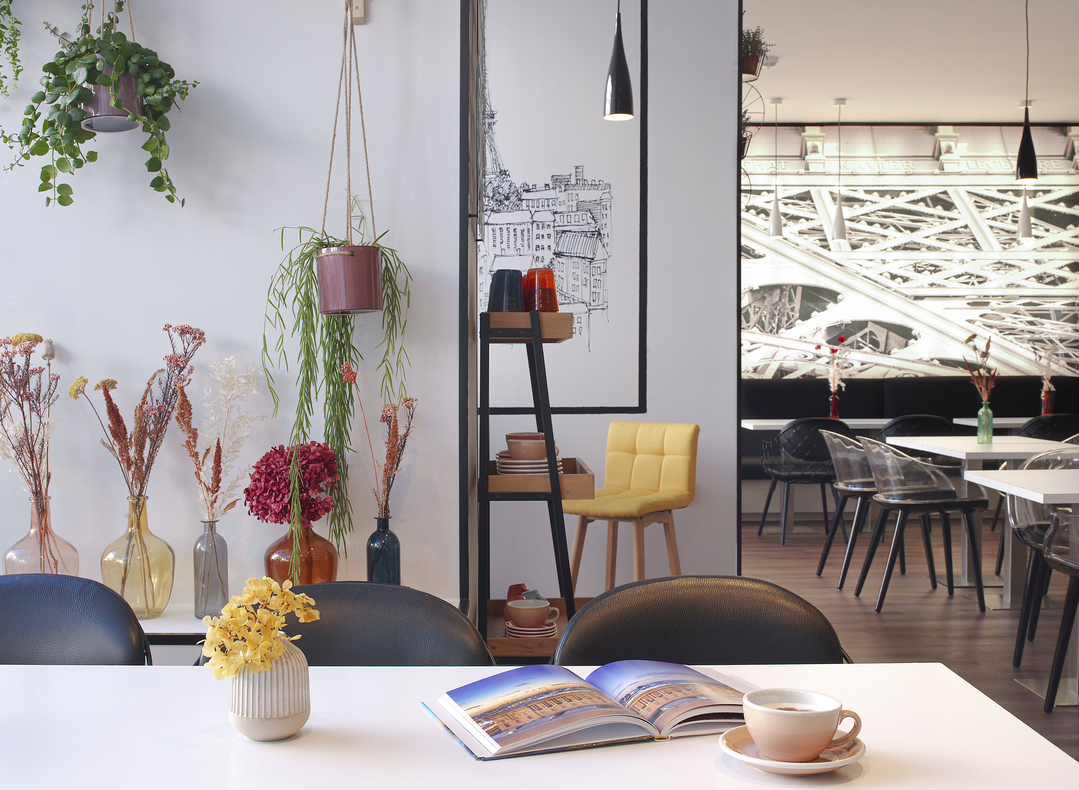 Modern cafe with Parisian decor, hanging plants, coffee cup, and dining tables.