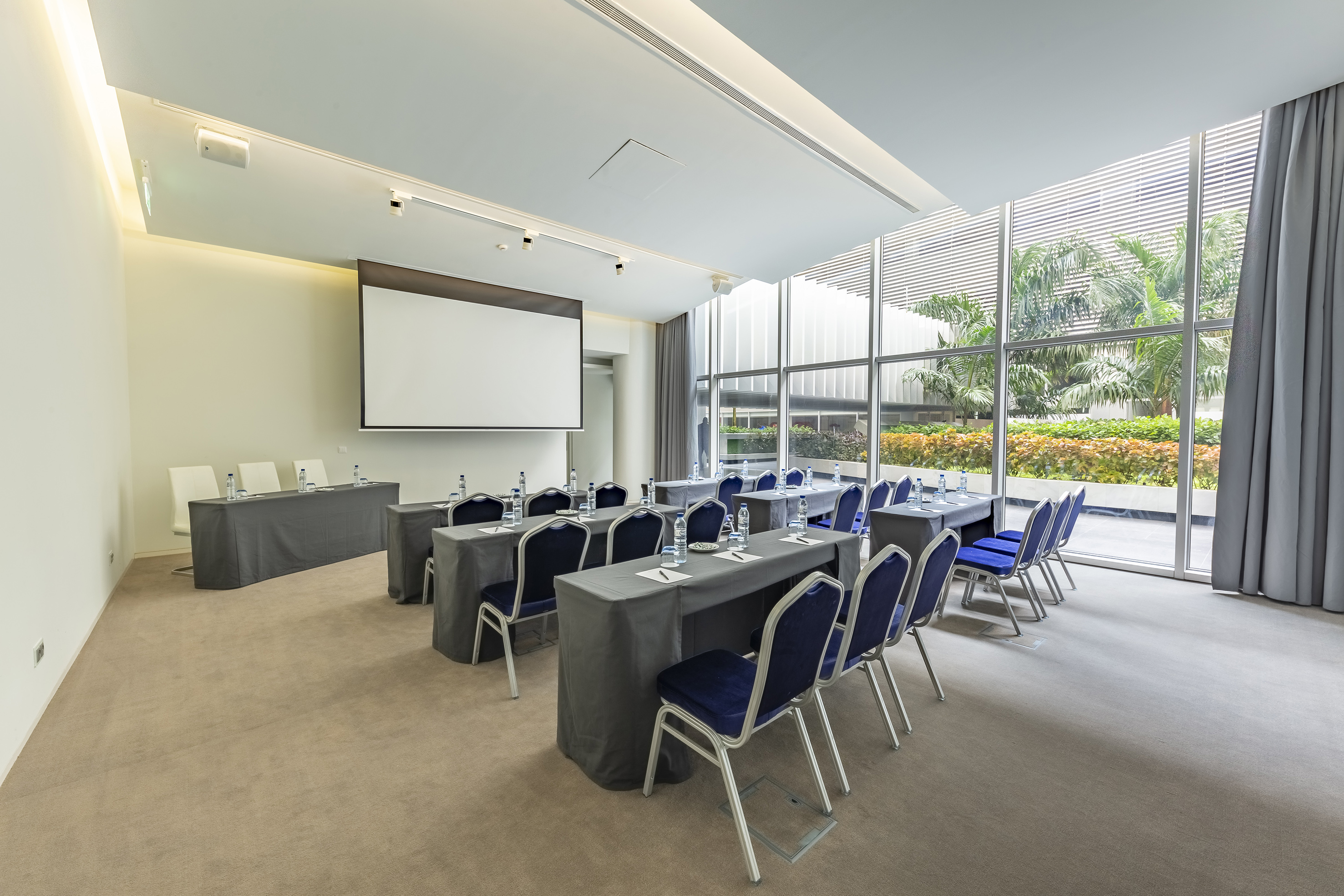 Bright conference room with projector screen, blue chairs, and large windows. - Sala Polana - Meliá Maputo Sky, Maputo