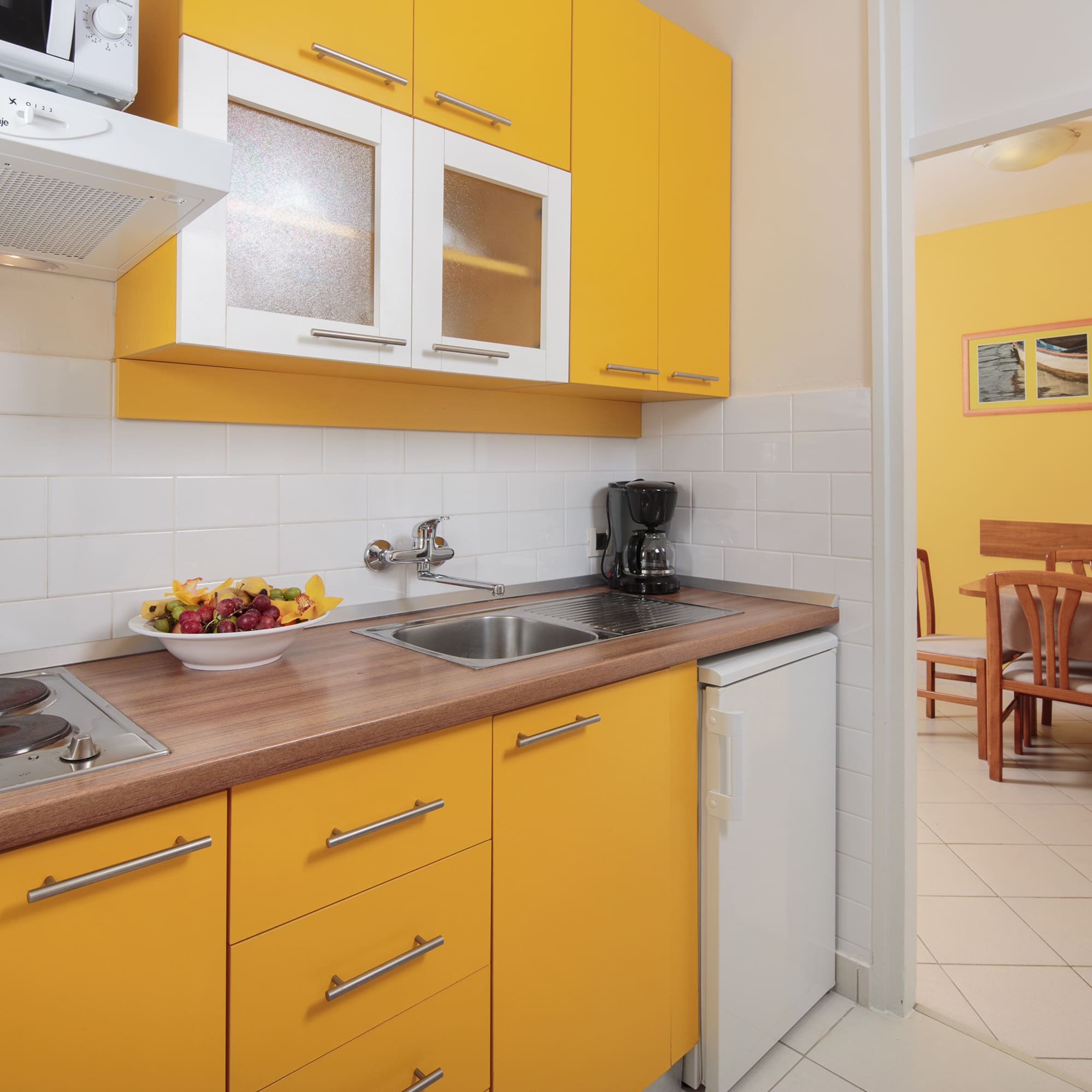 a kitchen with yellow cabinets and a white tile floor