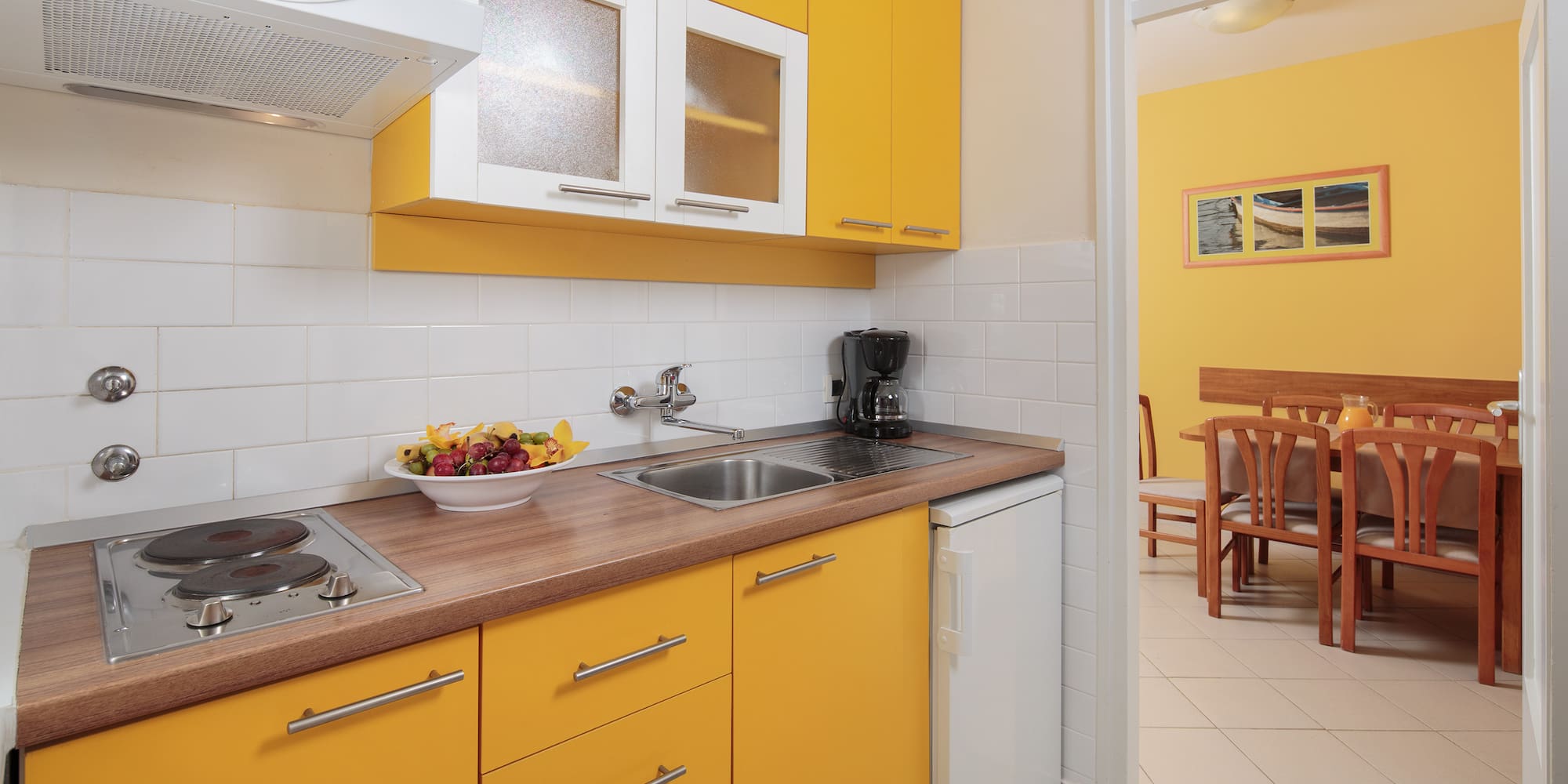 a kitchen with yellow cabinets and a white tile floor