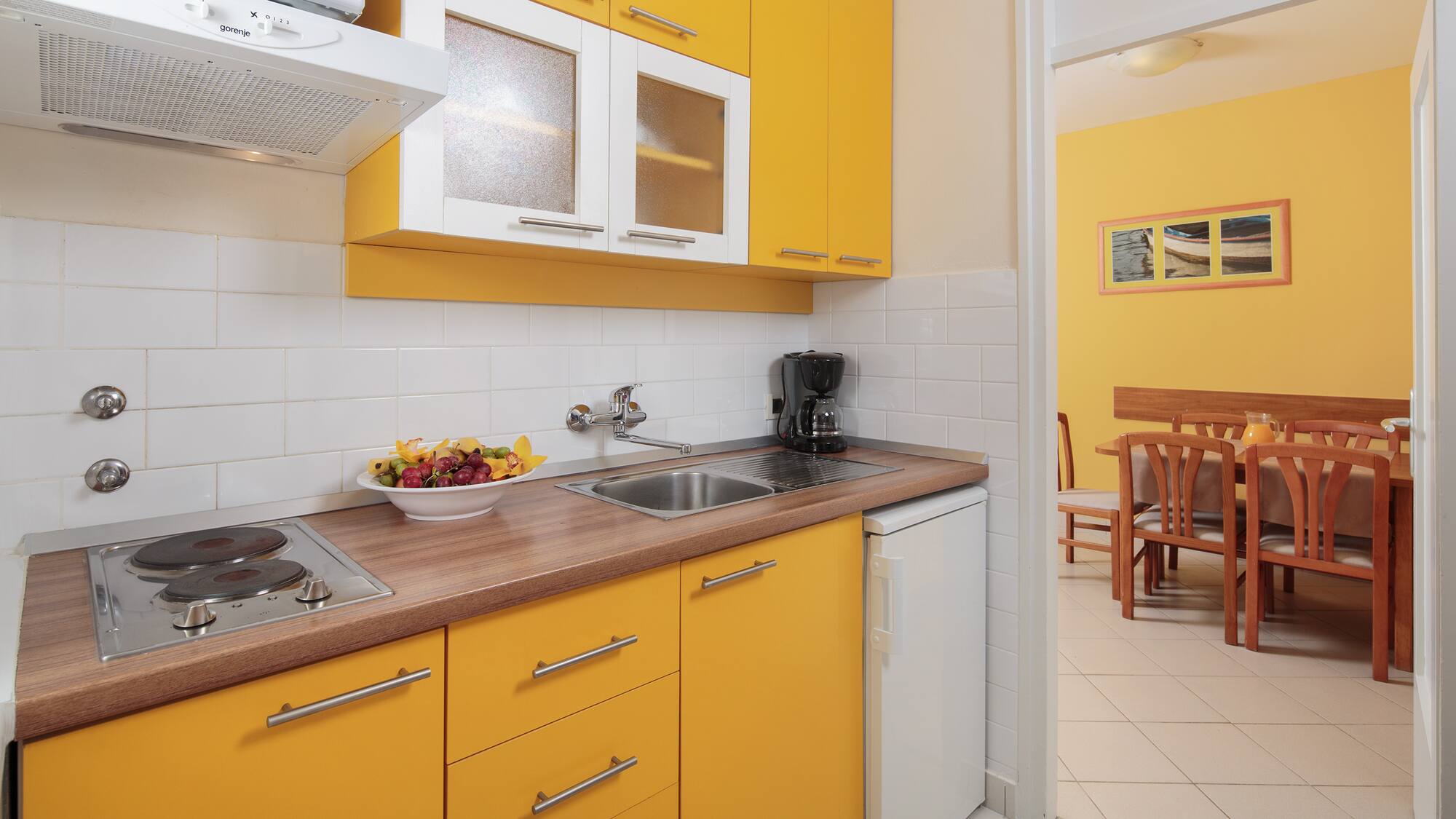 a kitchen with yellow cabinets and a white tile floor