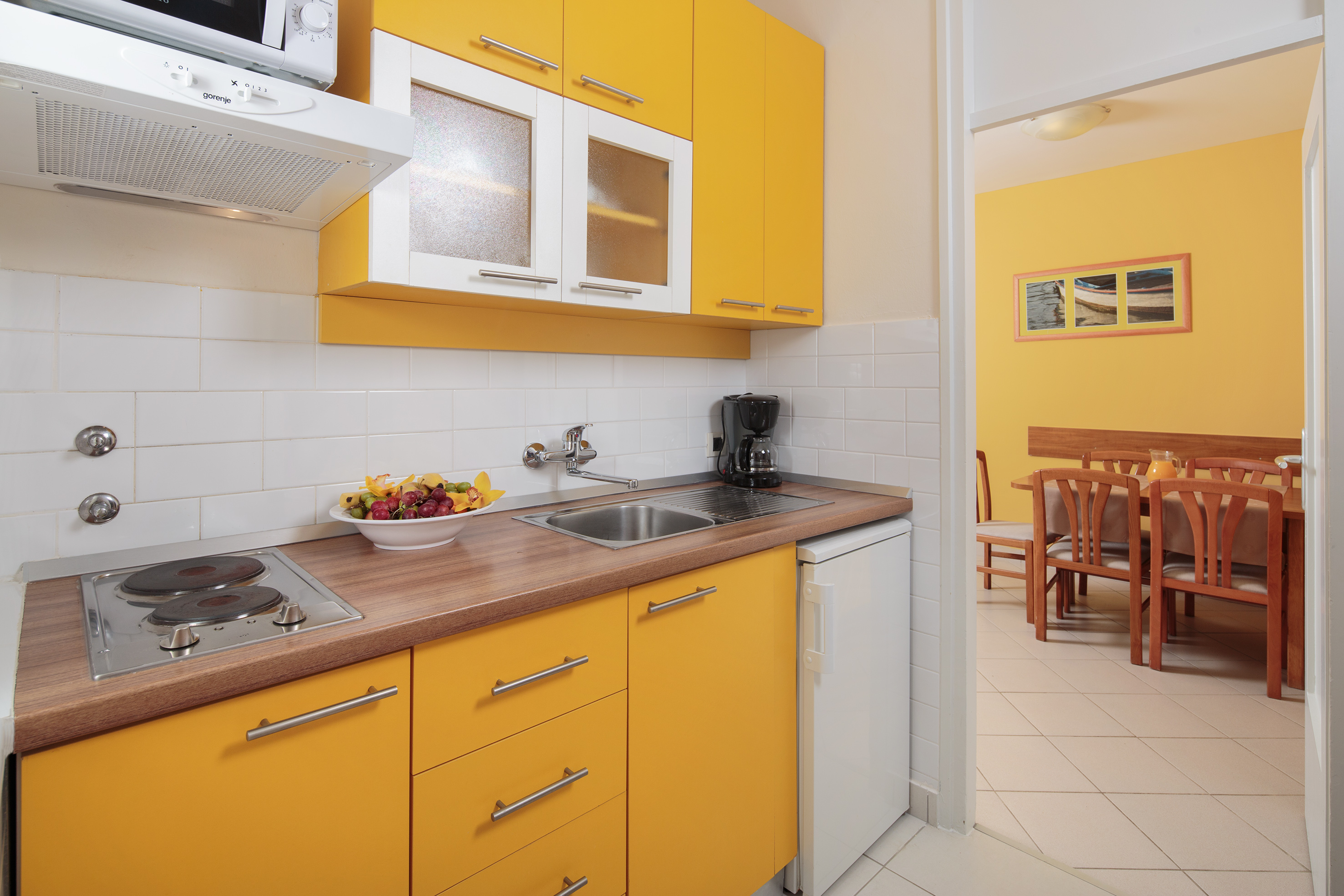 a kitchen with yellow cabinets and a white tile floor