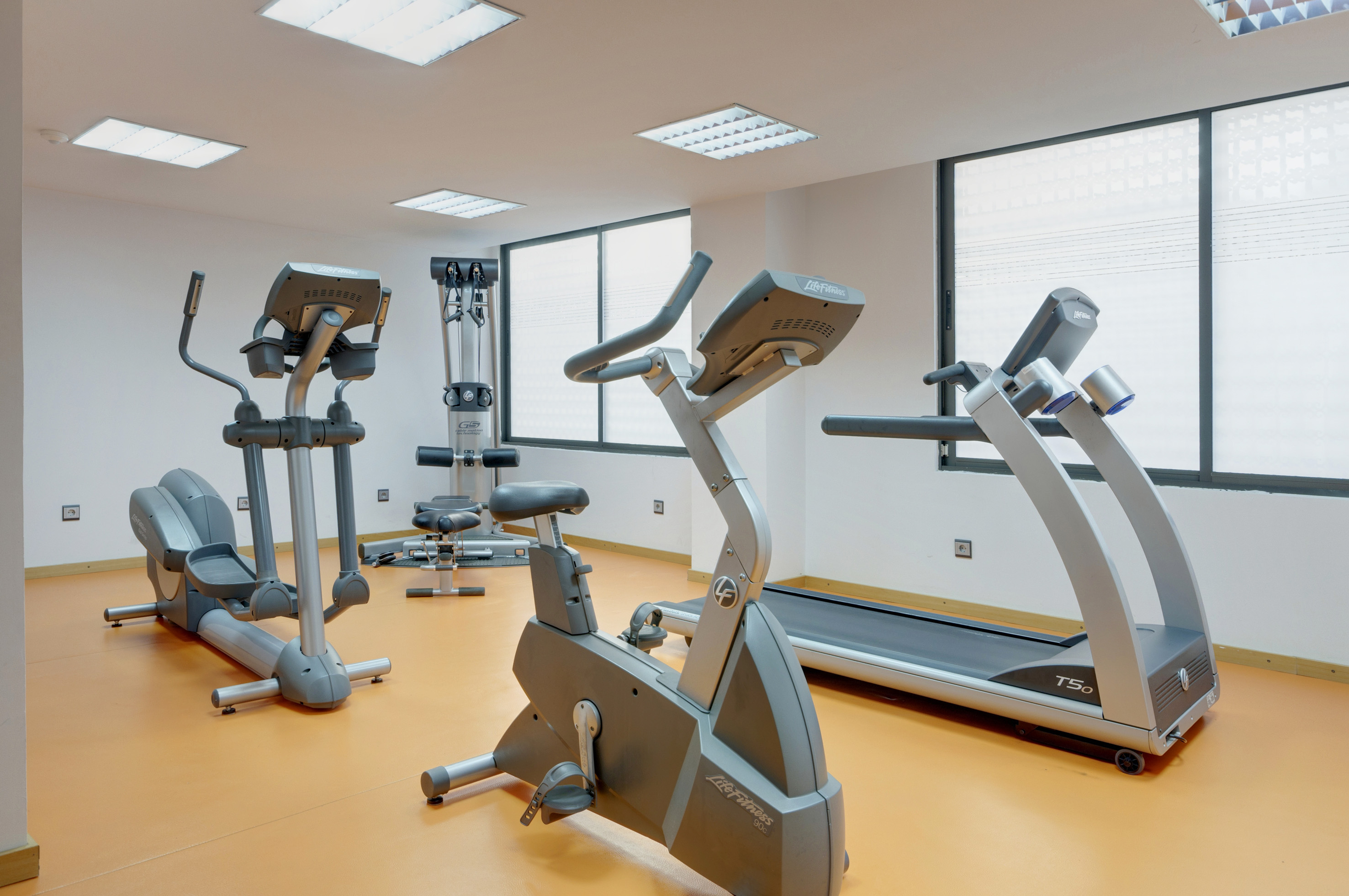 Gym with elliptical, exercise bike, treadmill, and weight equipment.