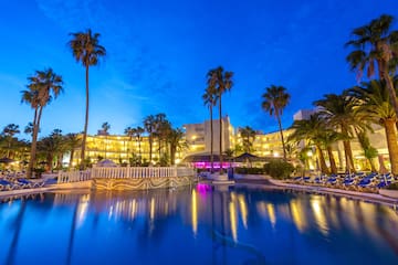 a pool with palm trees and buildings in the background