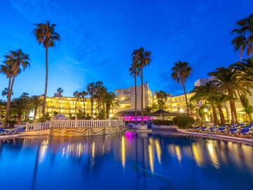 a pool with palm trees and buildings in the background