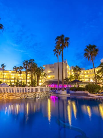 a pool with palm trees and buildings in the background