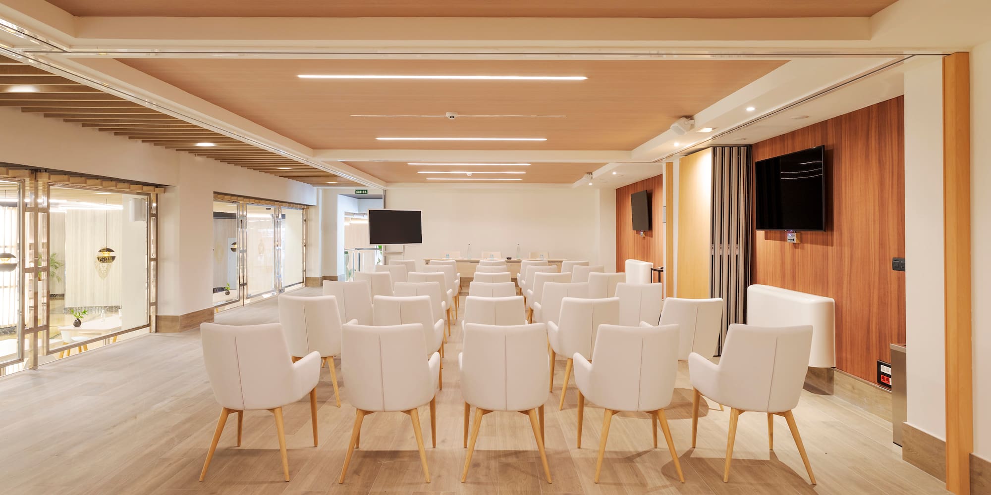 a room with white chairs and a television