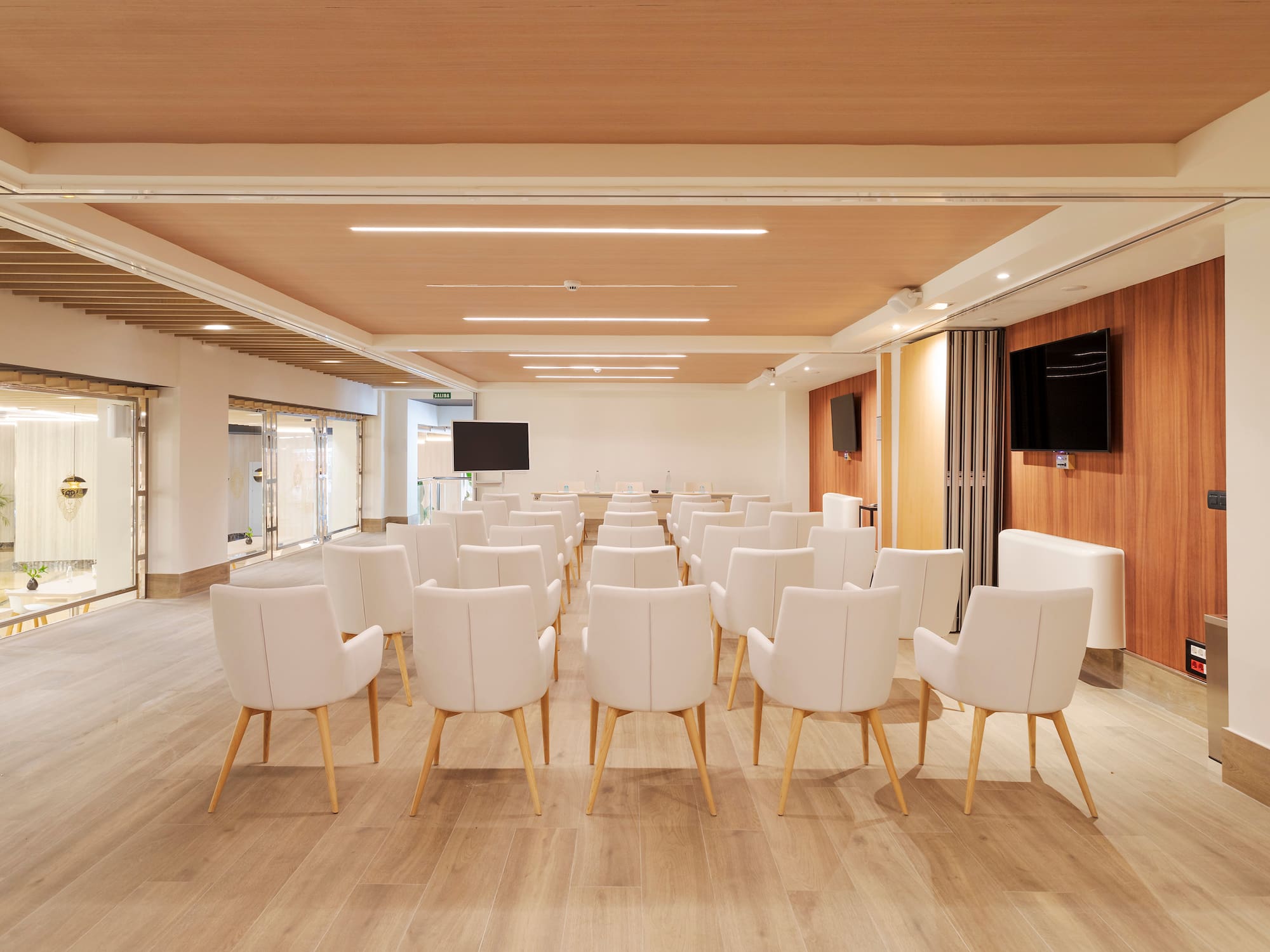 a room with white chairs and a television