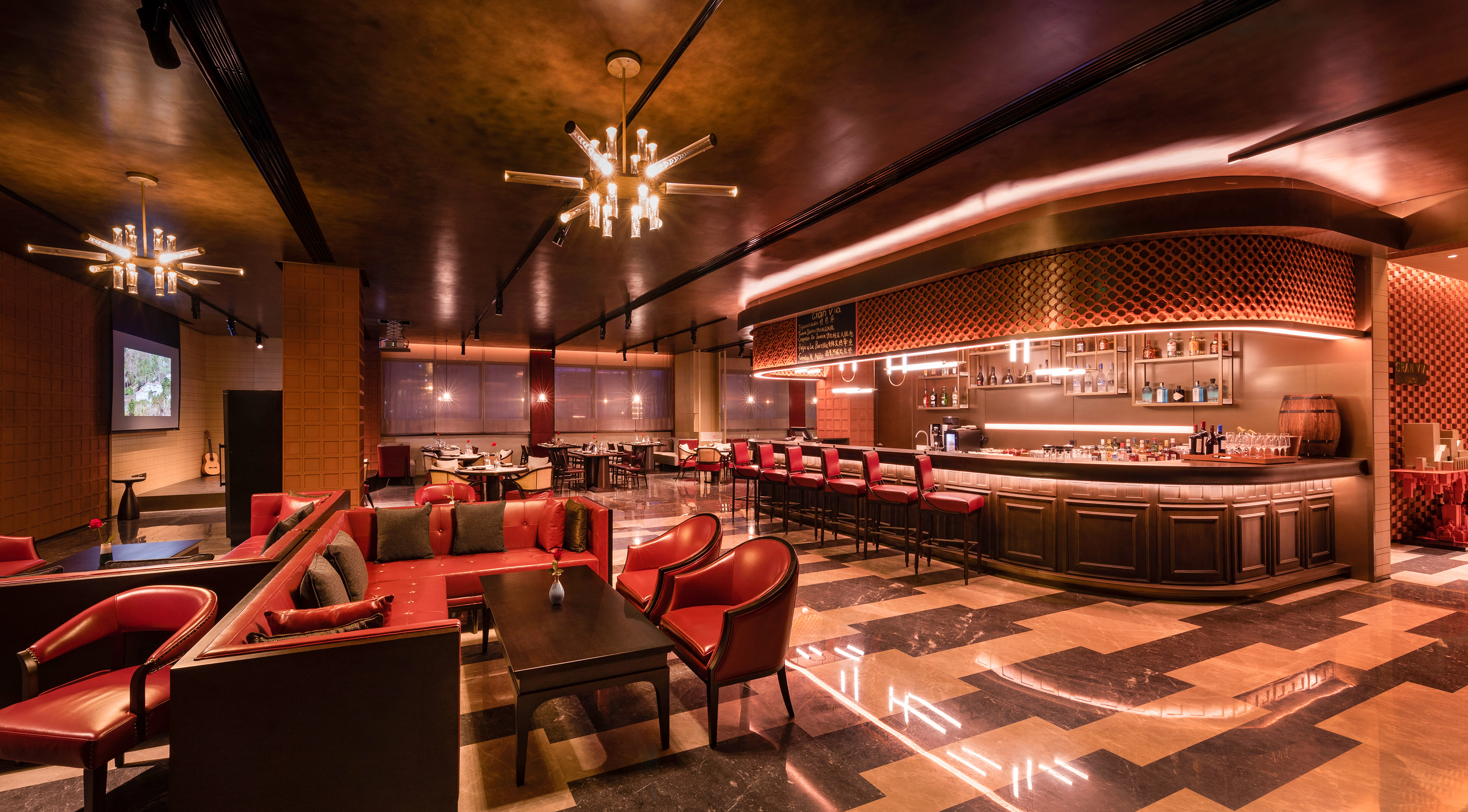 Luxury bar lounge interior, red seating, modern lighting, dark wood bar.