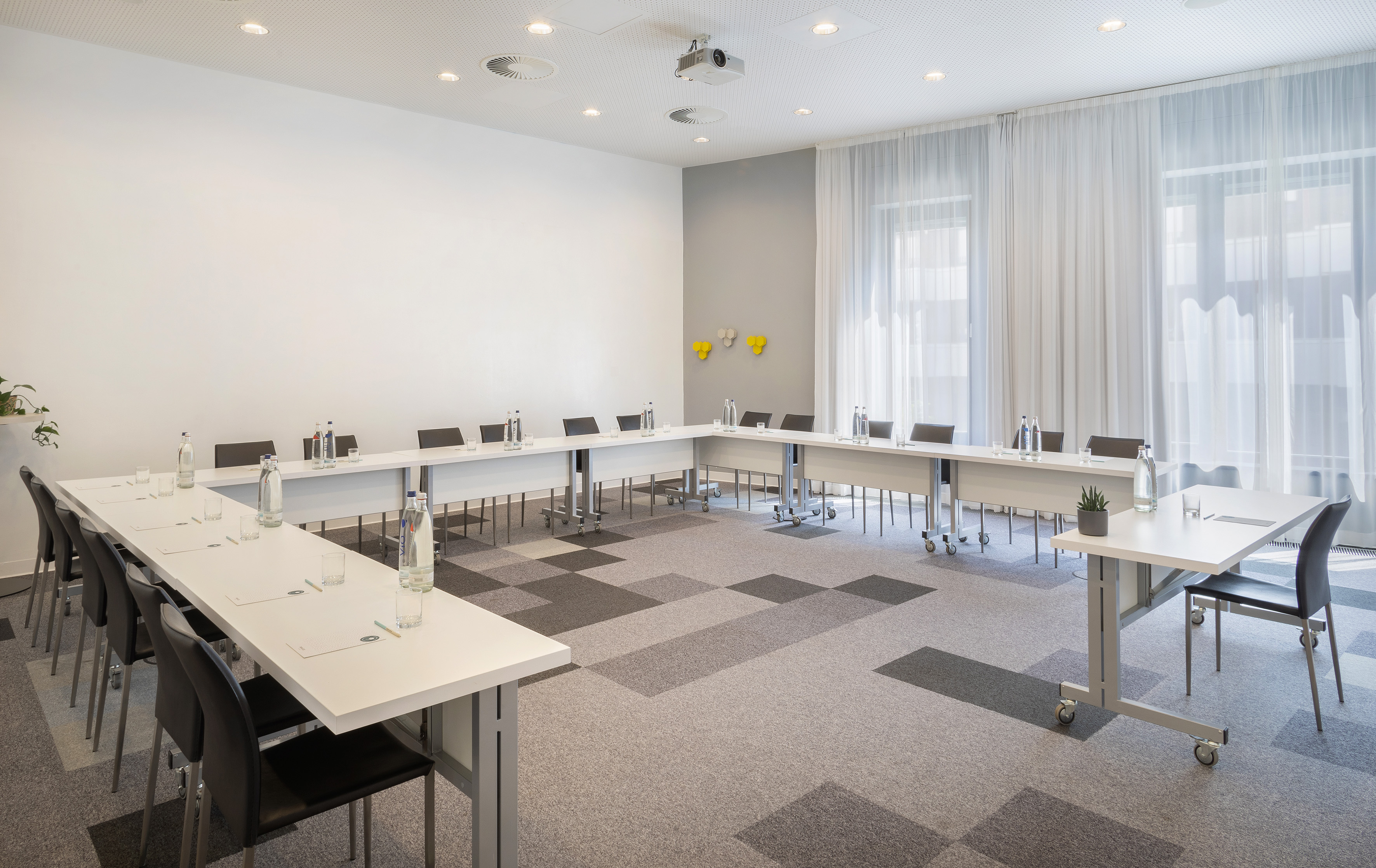 Modern U-shape meeting room with projector, tables, chairs for conferences.