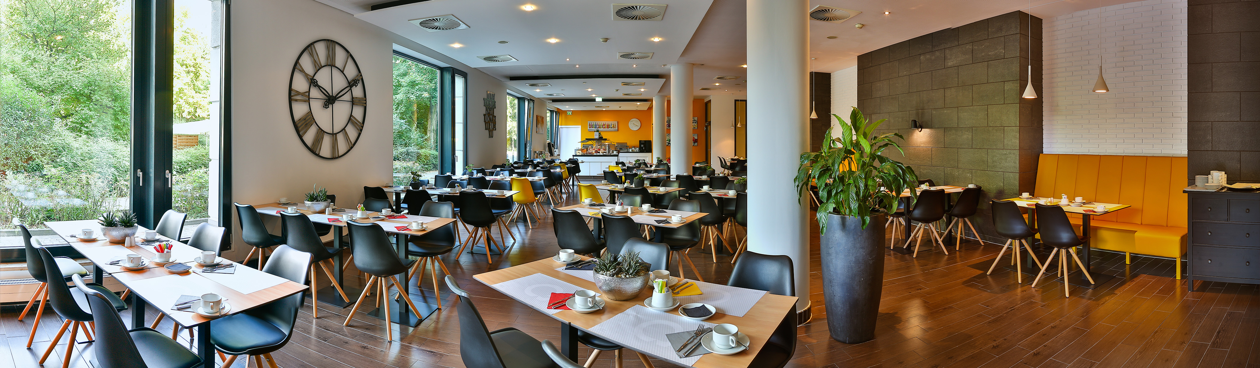 Bright modern hotel dining room with tables, large windows, and buffet.