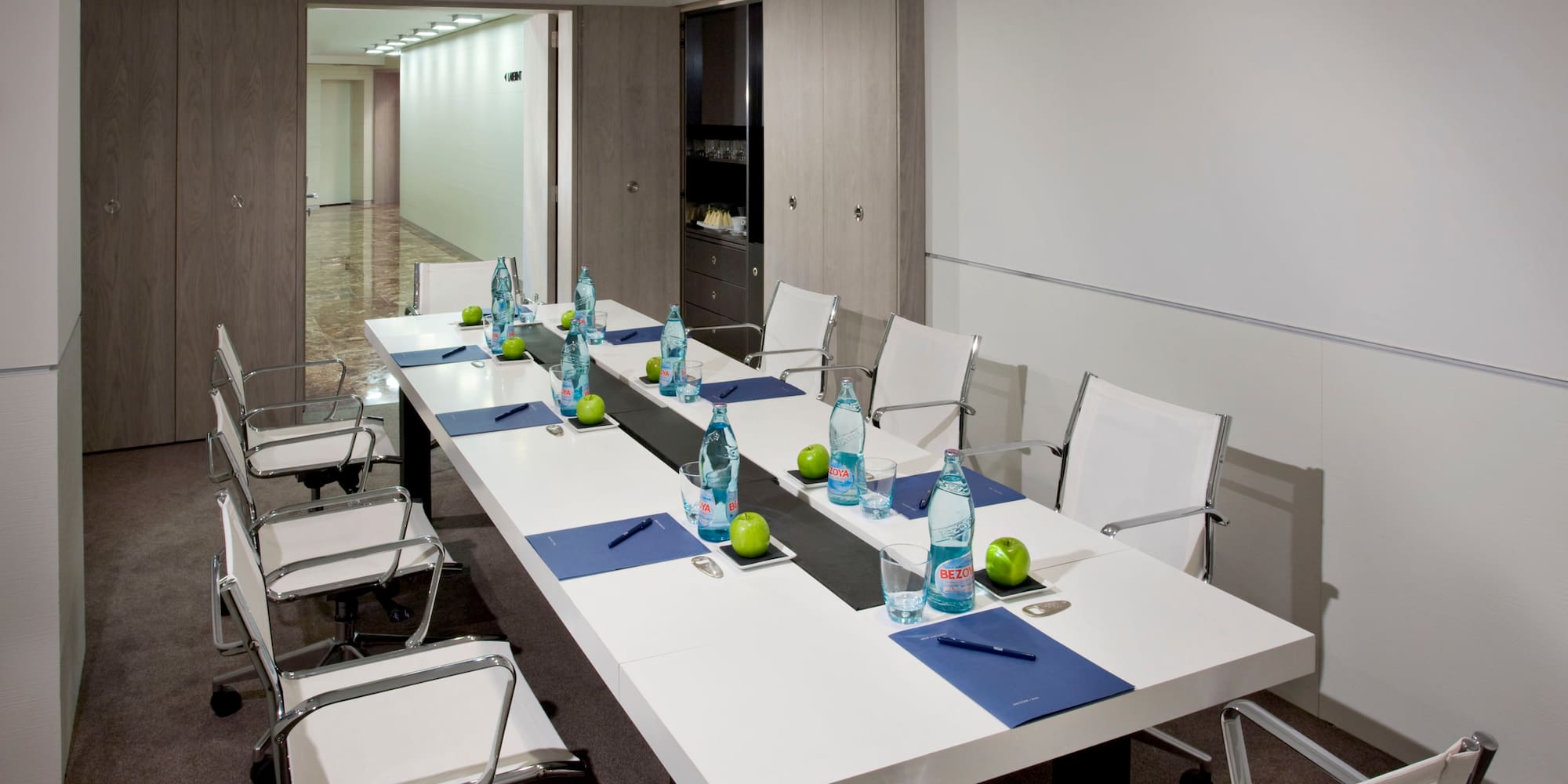 a long white table with chairs and water bottles on it
