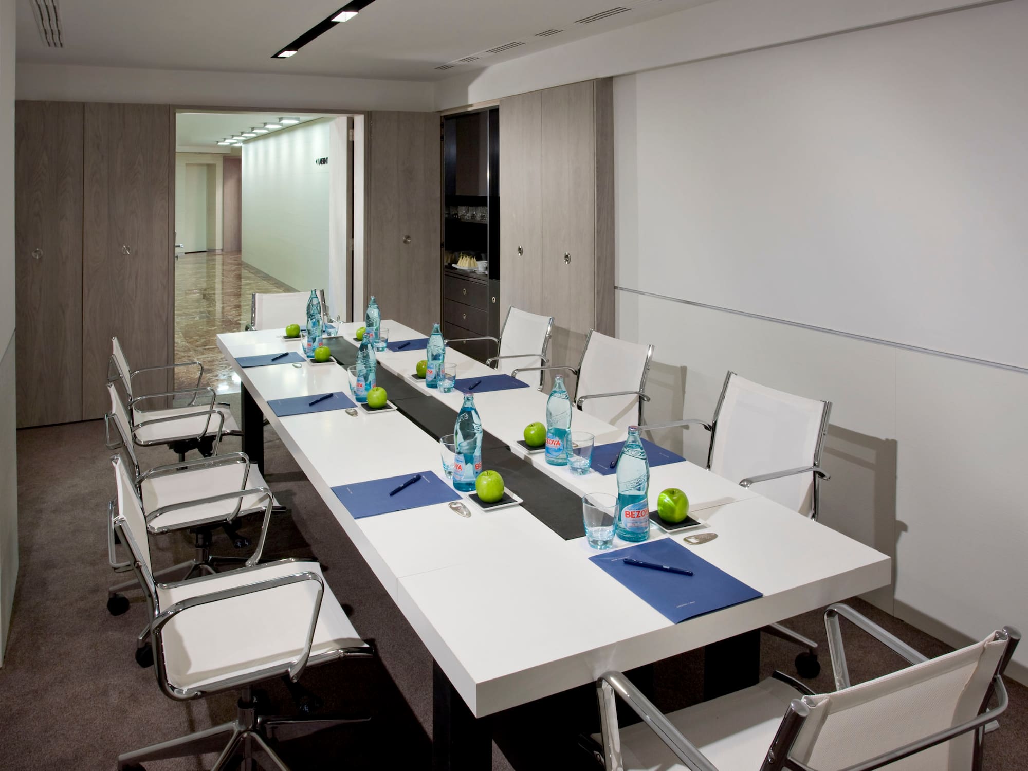 a long white table with chairs and water bottles on it