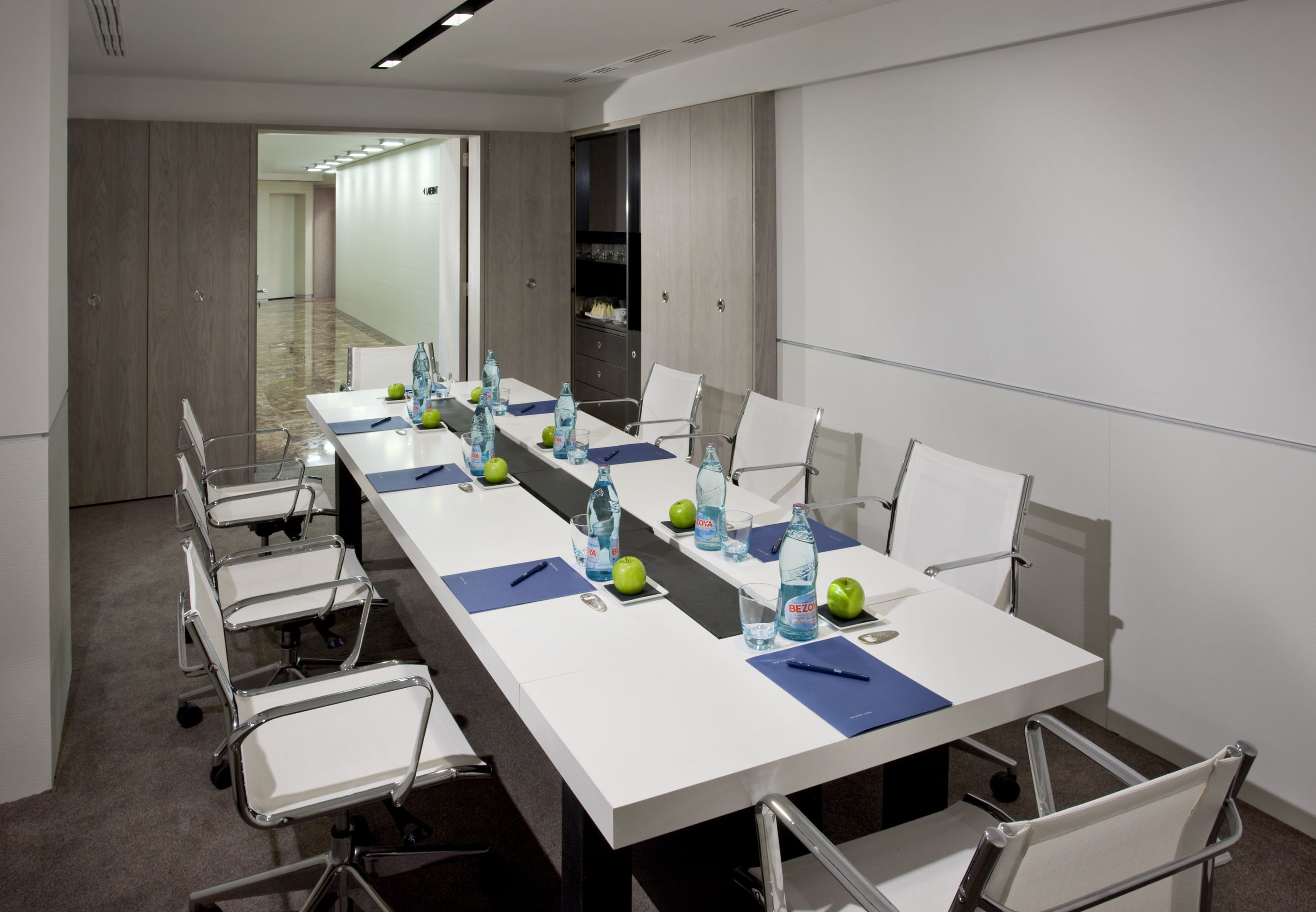 Contemporary meeting room with white table, chairs, and refreshments.