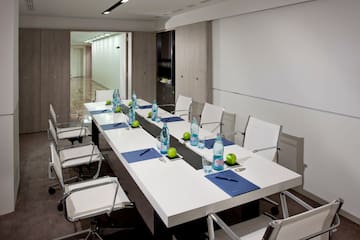 a long white table with chairs and water bottles on it