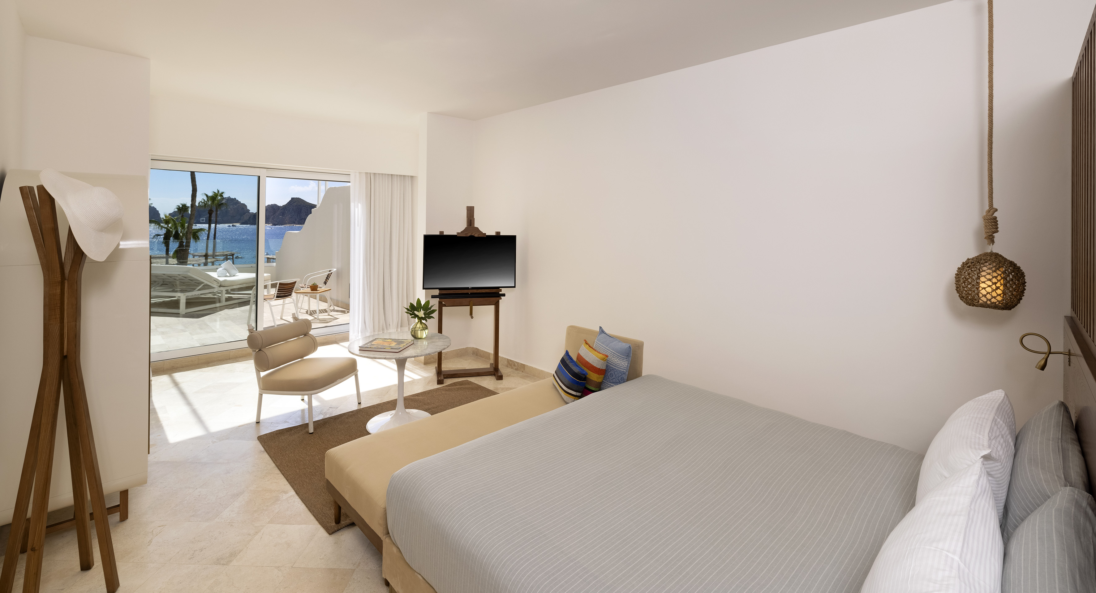 Oceanfront hotel room with balcony, bed, and tropical sea view.