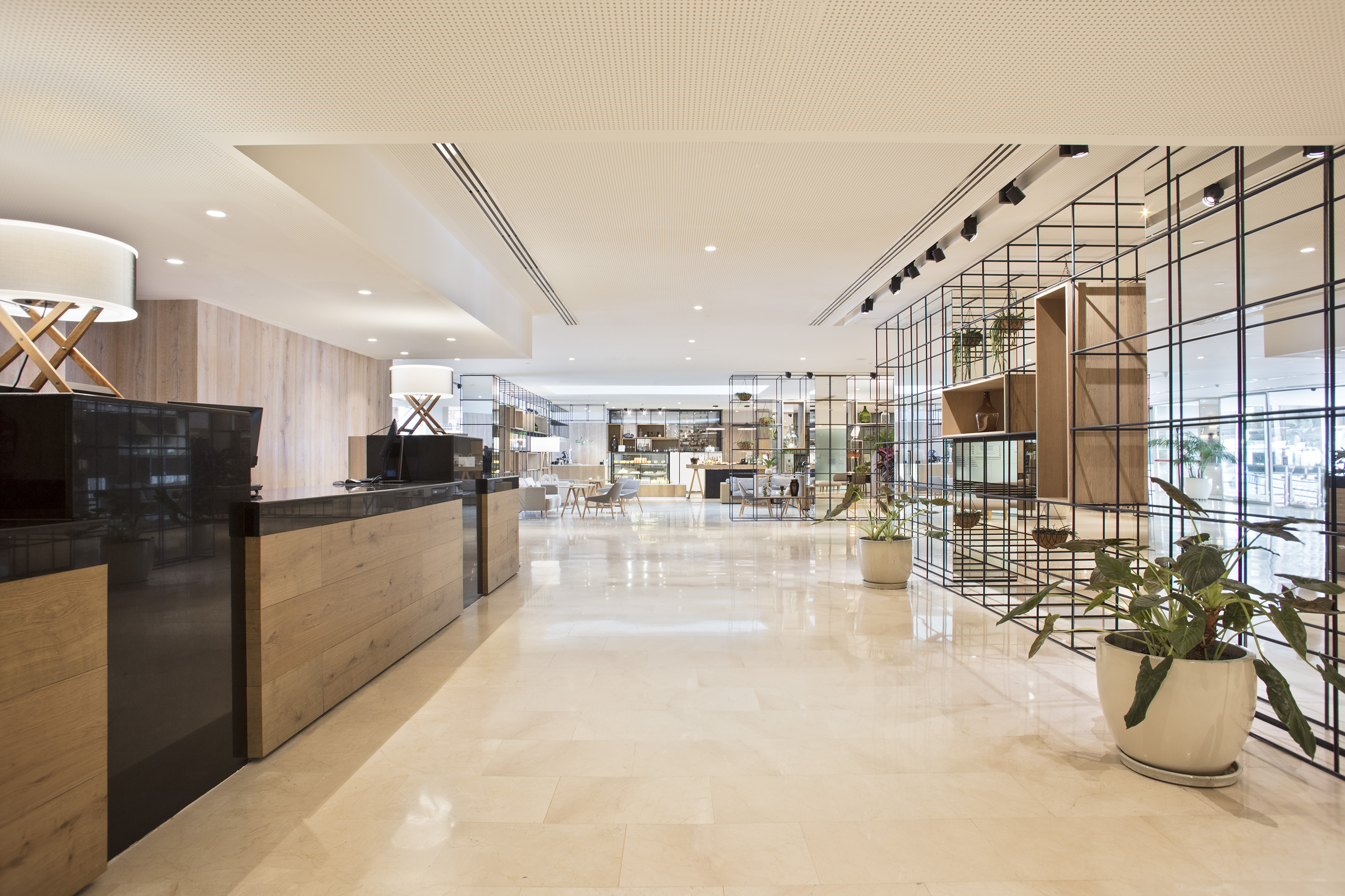 Sleek hotel lobby with reception desk, polished marble floor, and cafe area.