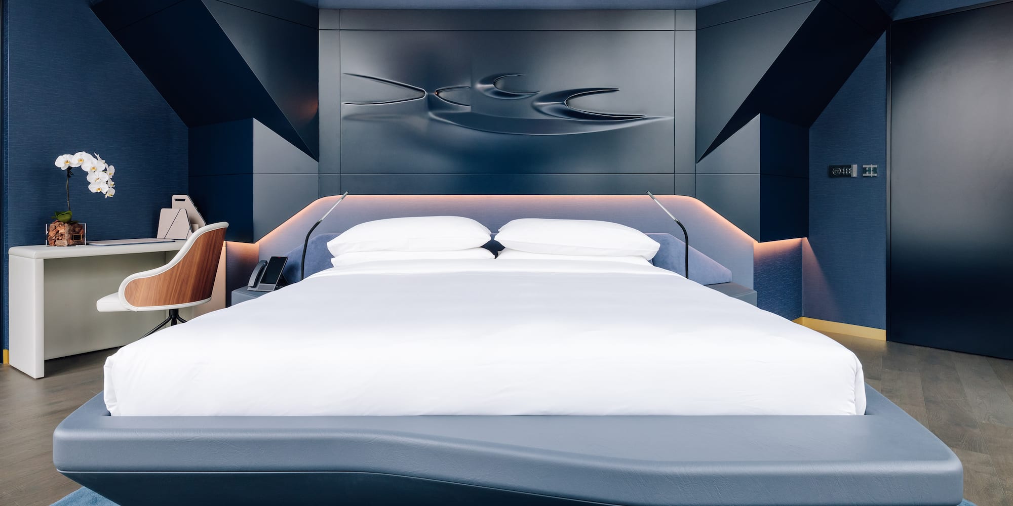 a bed with a white bedding and a blue wall