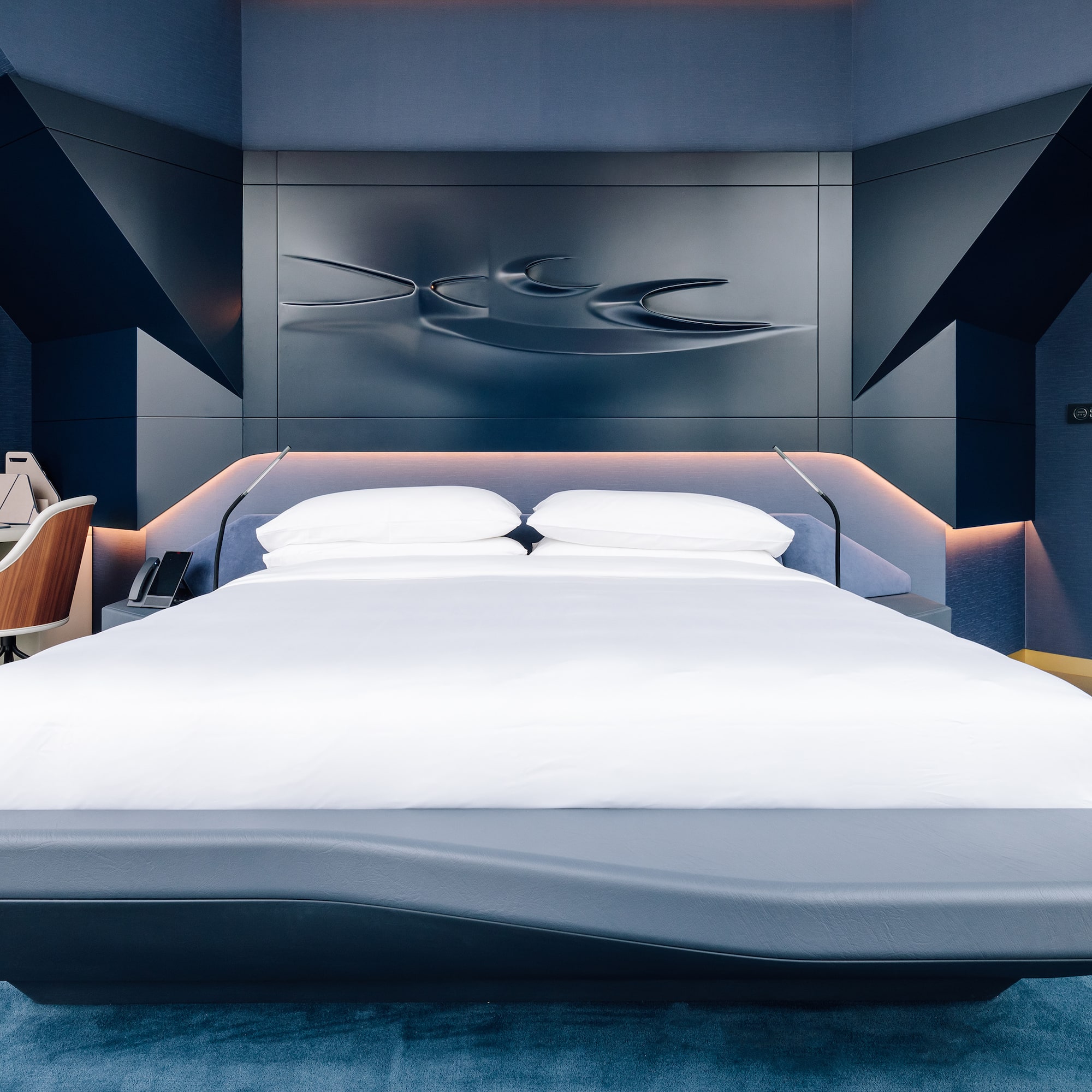a bed with a white bedding and a blue wall