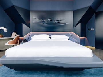 a bed with a white bedding and a blue wall