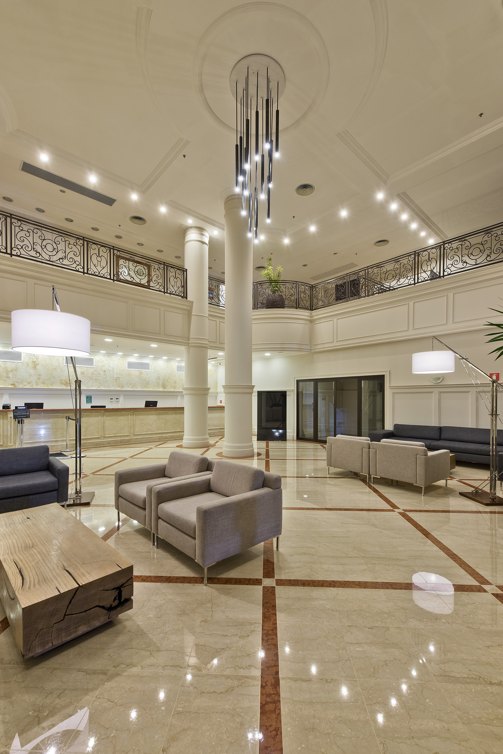 Luxury hotel lobby with modern chandelier, lounge seating, and marble floor.