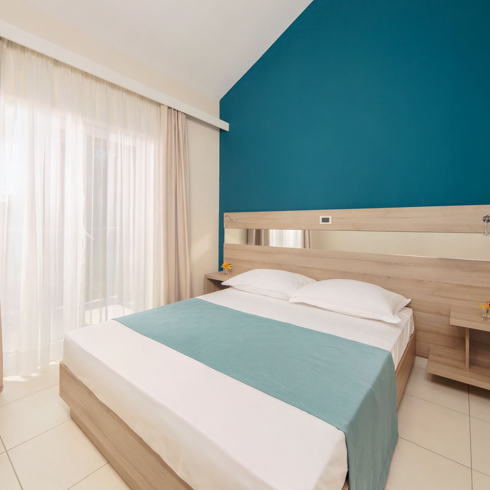 a bedroom with a blue wall and white curtains