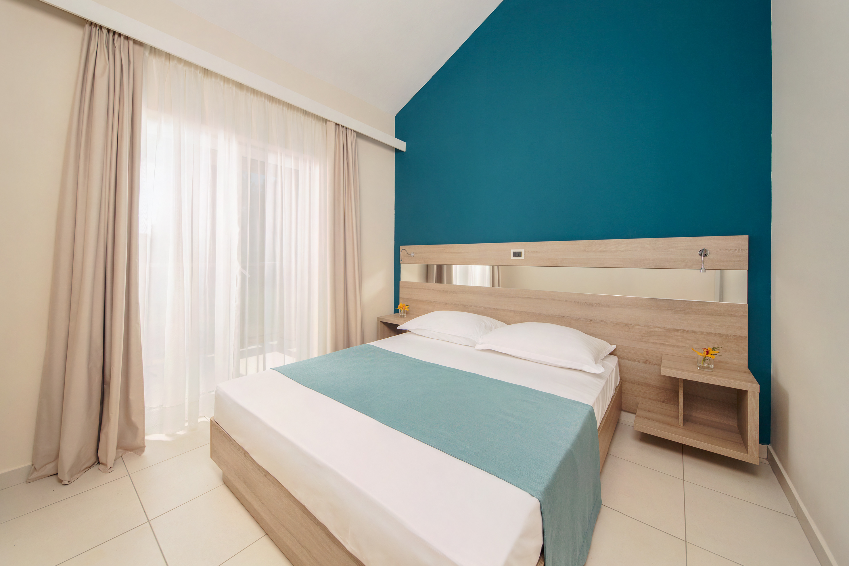 a bedroom with a blue wall and white curtains
