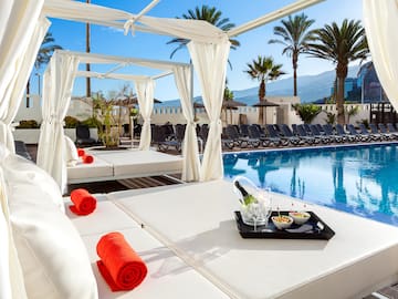 a pool with a white canopy and a tray of food on it