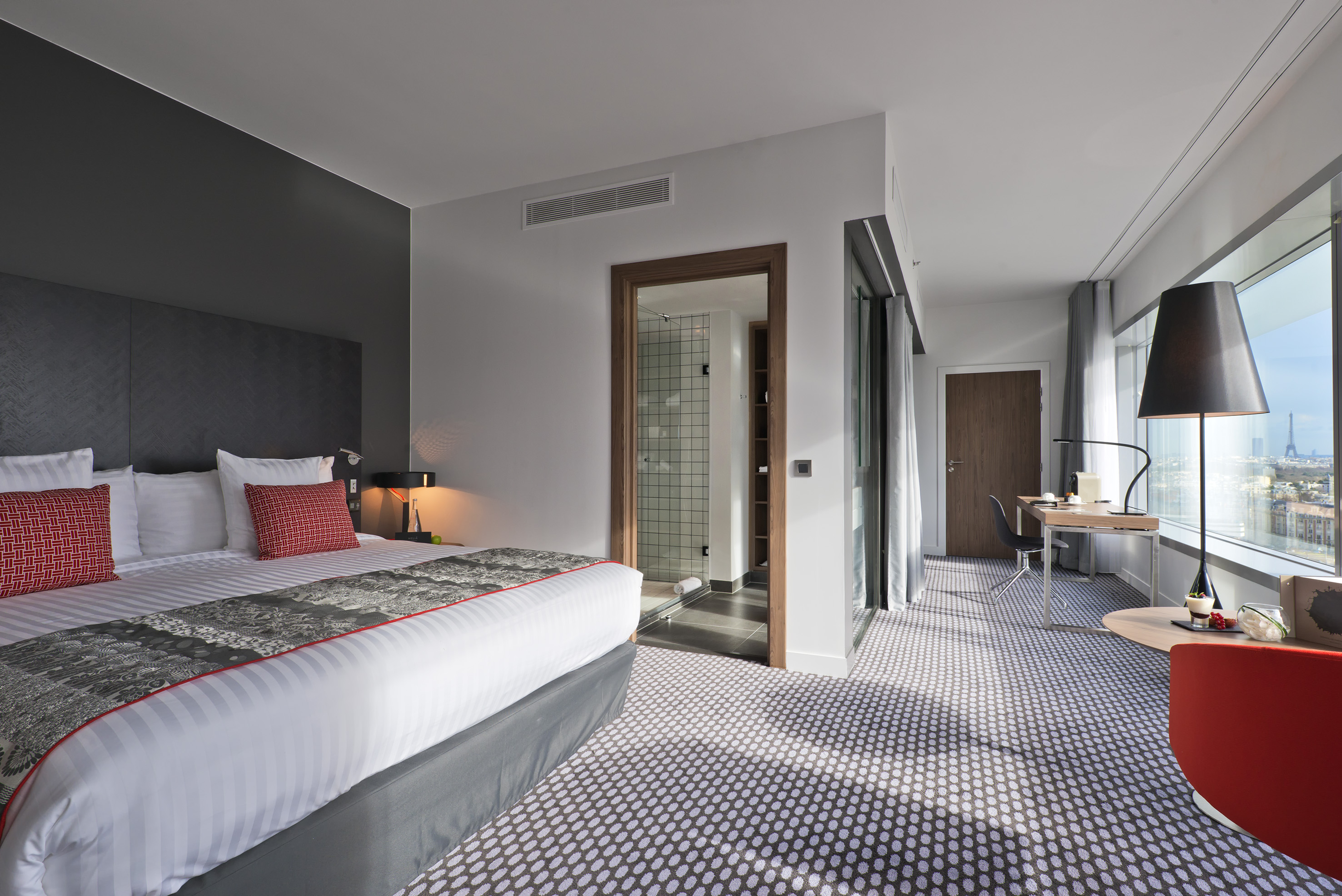 Stylish hotel room with Paris city view, Eiffel Tower, king bed, and desk area.