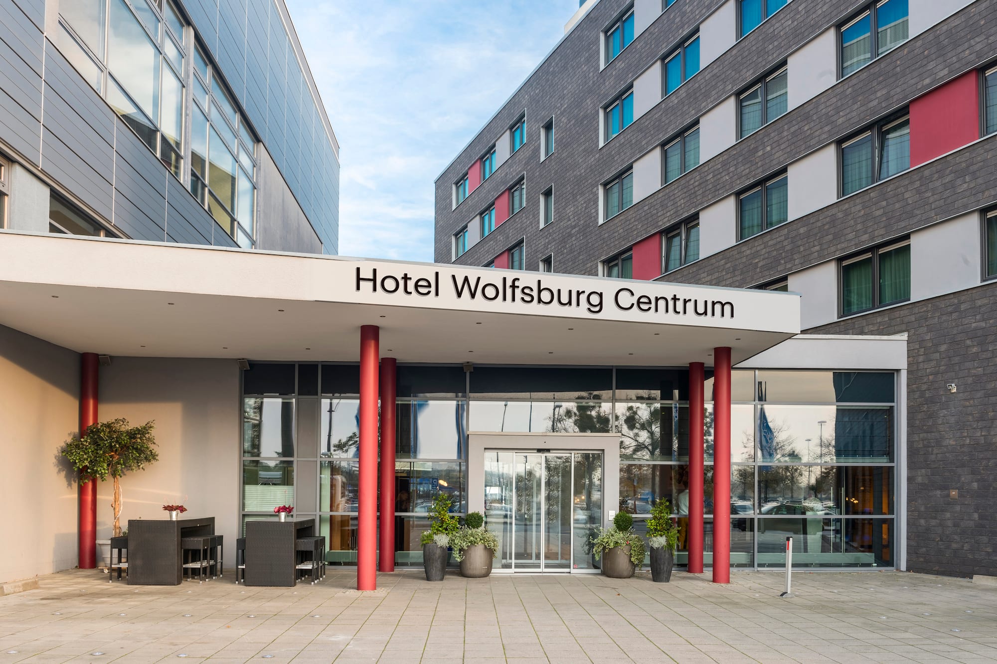 Hotel Wolfsburg Centrum entrance, modern building with glass doors, red pillars.