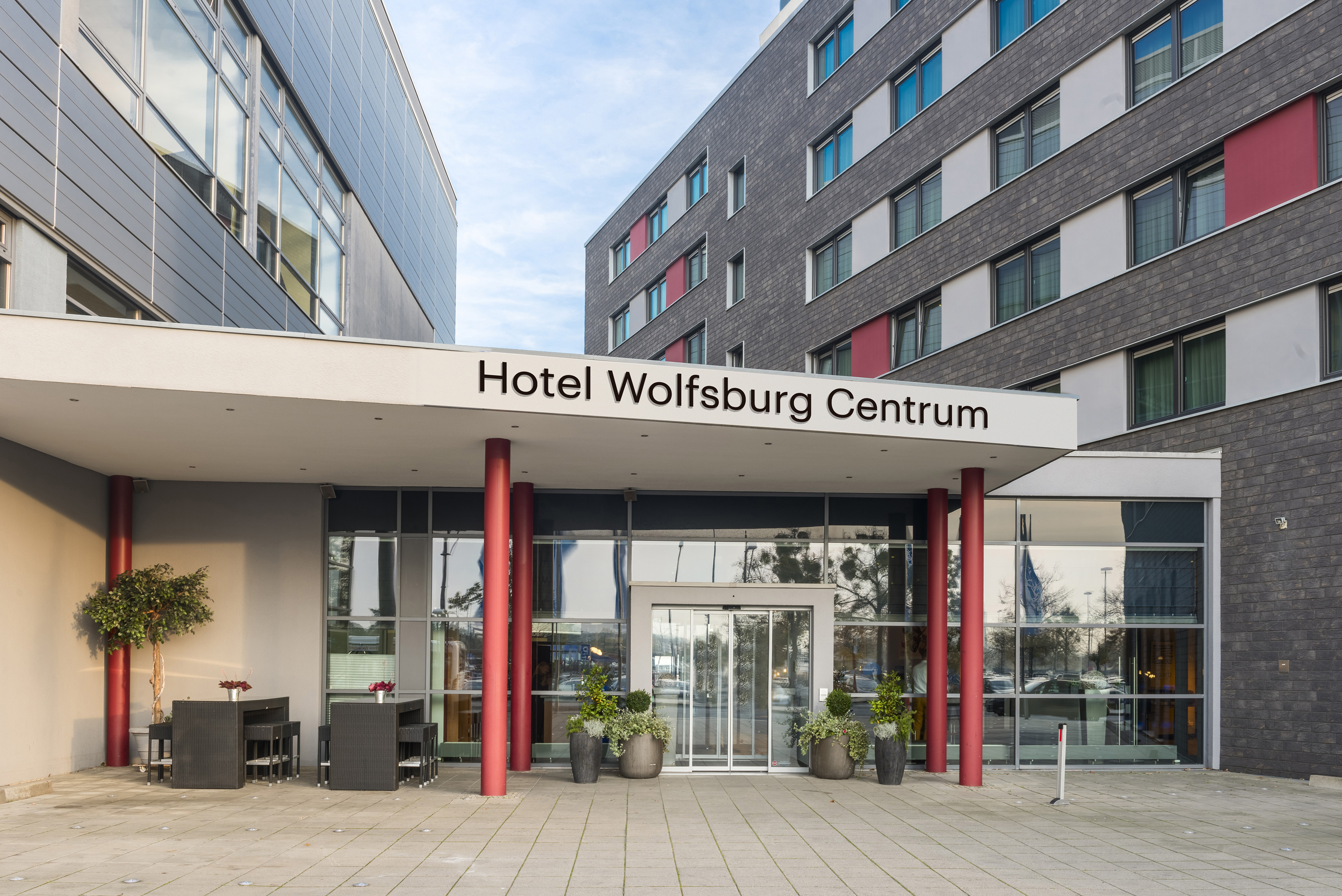 Hotel Wolfsburg Centrum entrance, modern building with glass doors, red pillars.