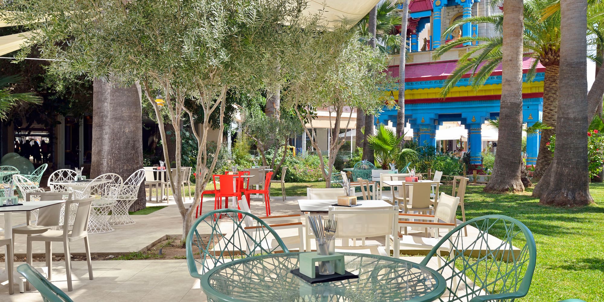 a table and chairs outside with trees and buildings in the background