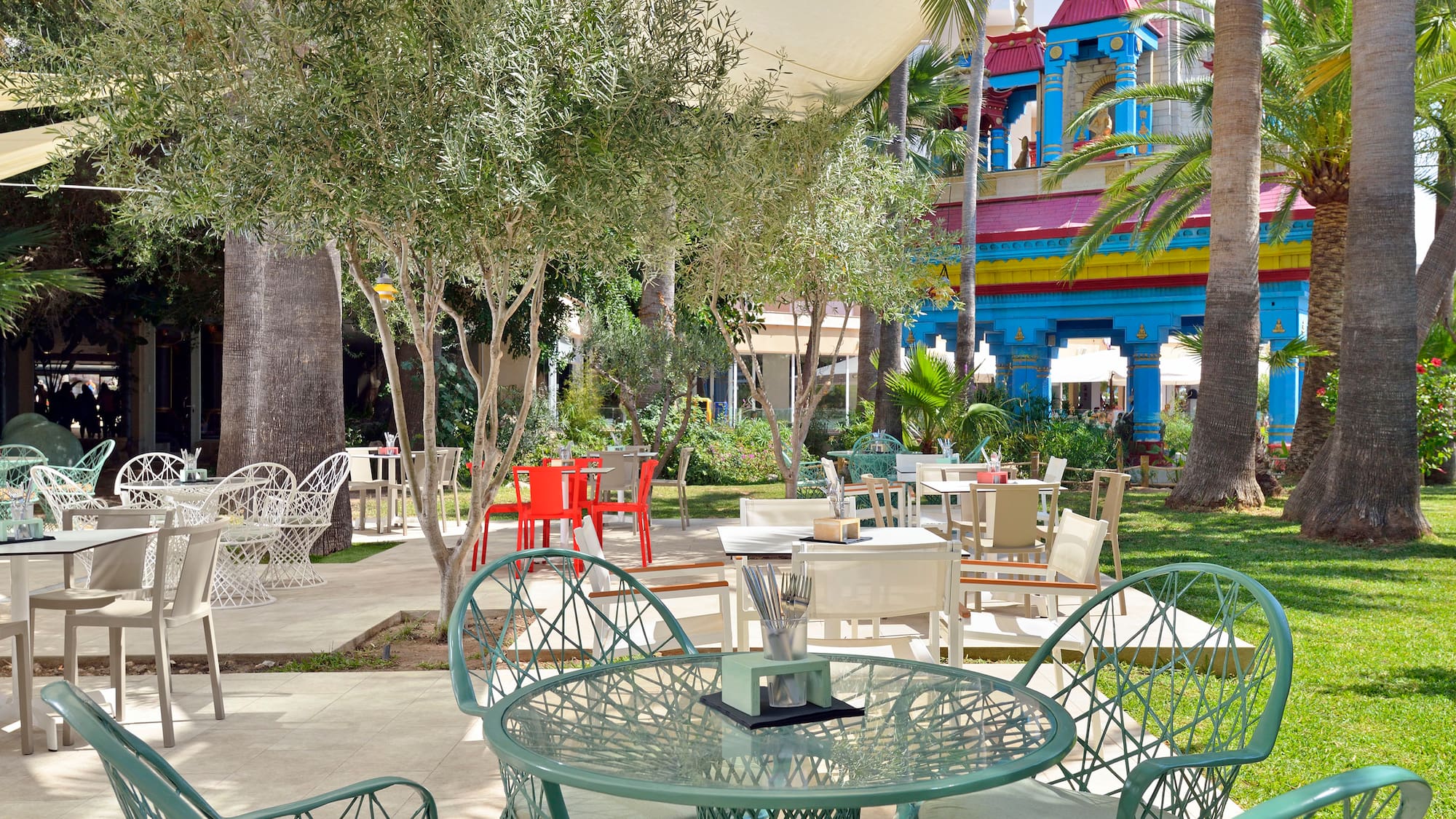 a table and chairs outside with trees and buildings in the background
