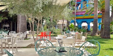 a table and chairs outside with trees and buildings in the background