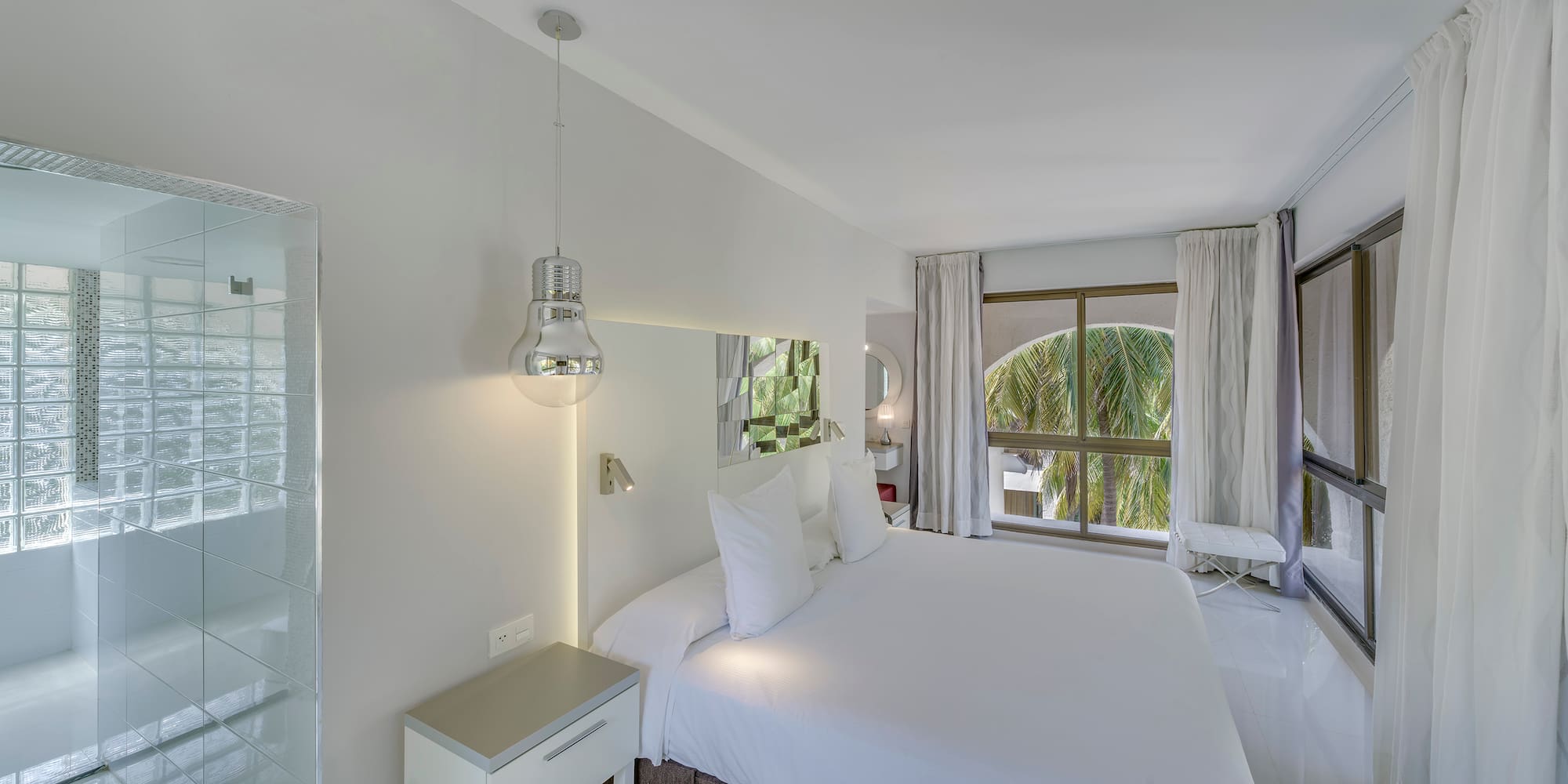 a white bed with white sheets and a mirror above it