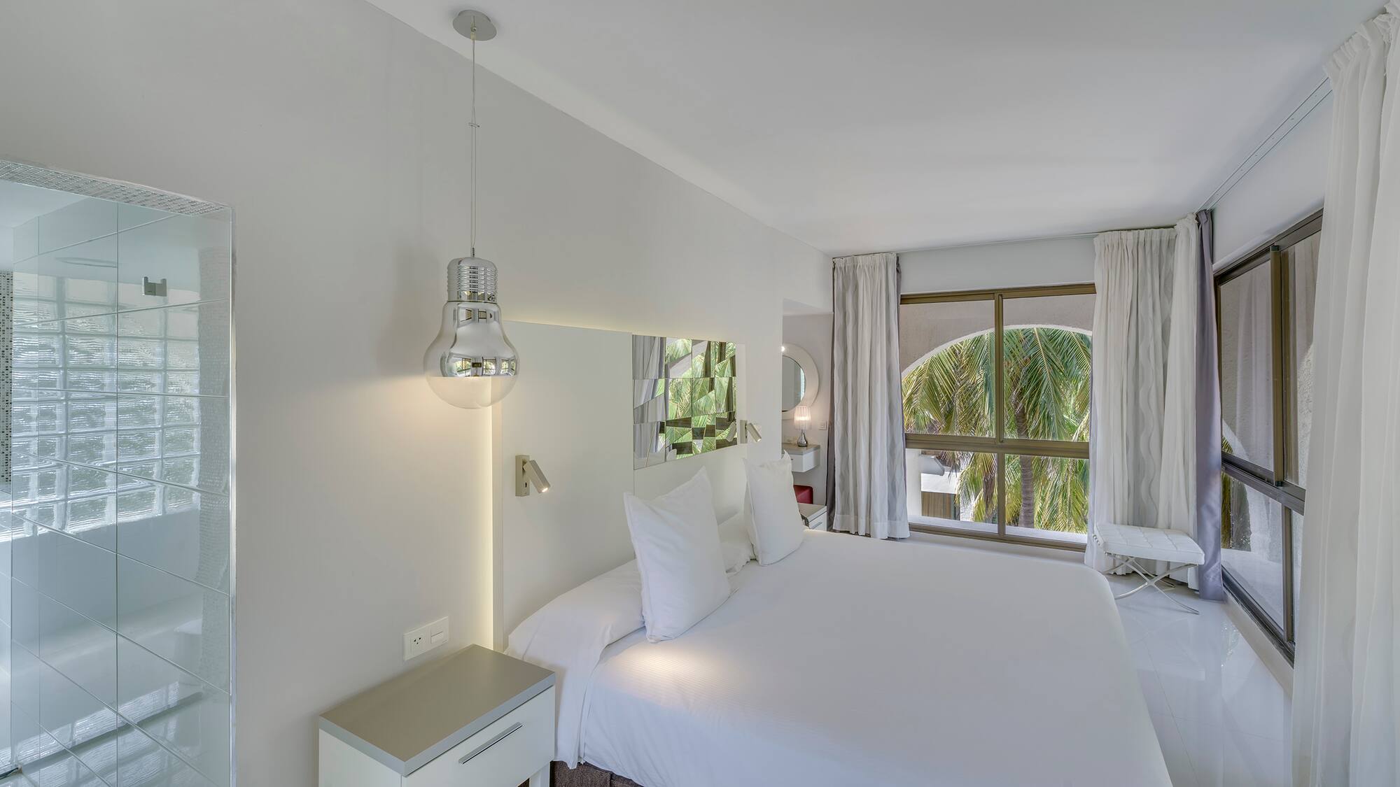 a white bed with white sheets and a mirror above it