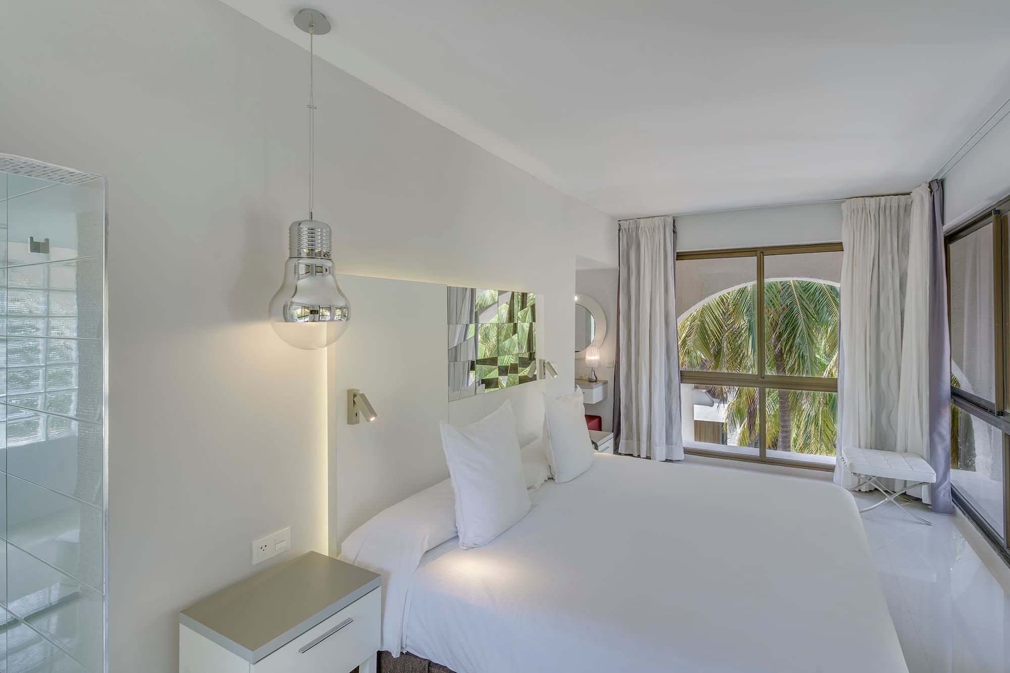 a white bed with white sheets and a mirror above it