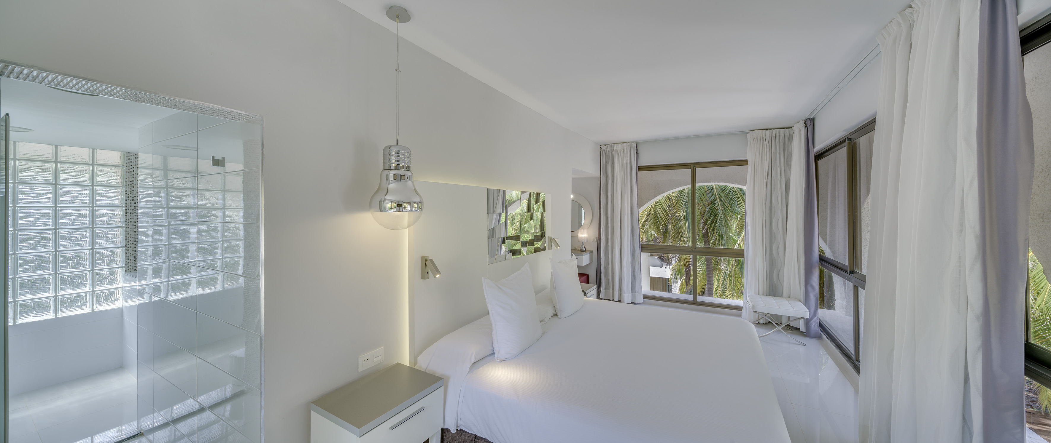 a white bed with white sheets and a mirror above it