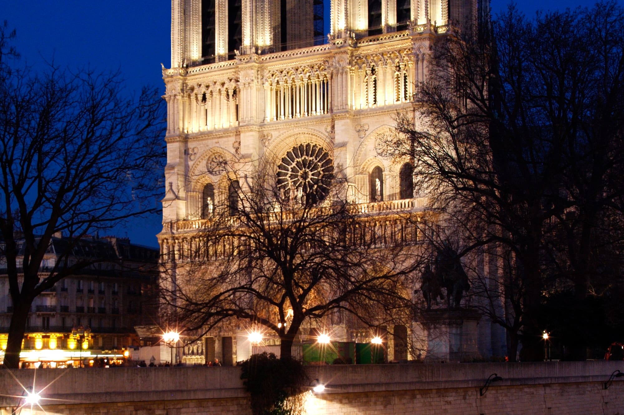 a large white building with lights on with Notre Dame de Paris in the background