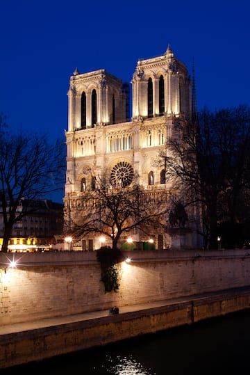 a large white building with lights on with Notre Dame de Paris in the background
