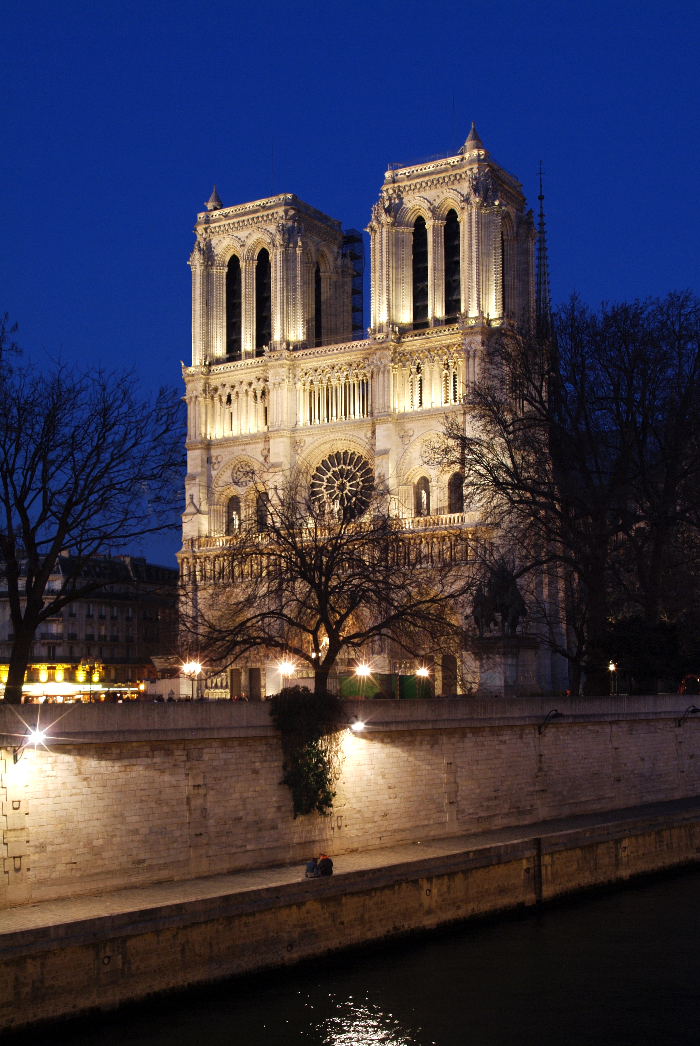 a large white building with lights on with Notre Dame de Paris in the background